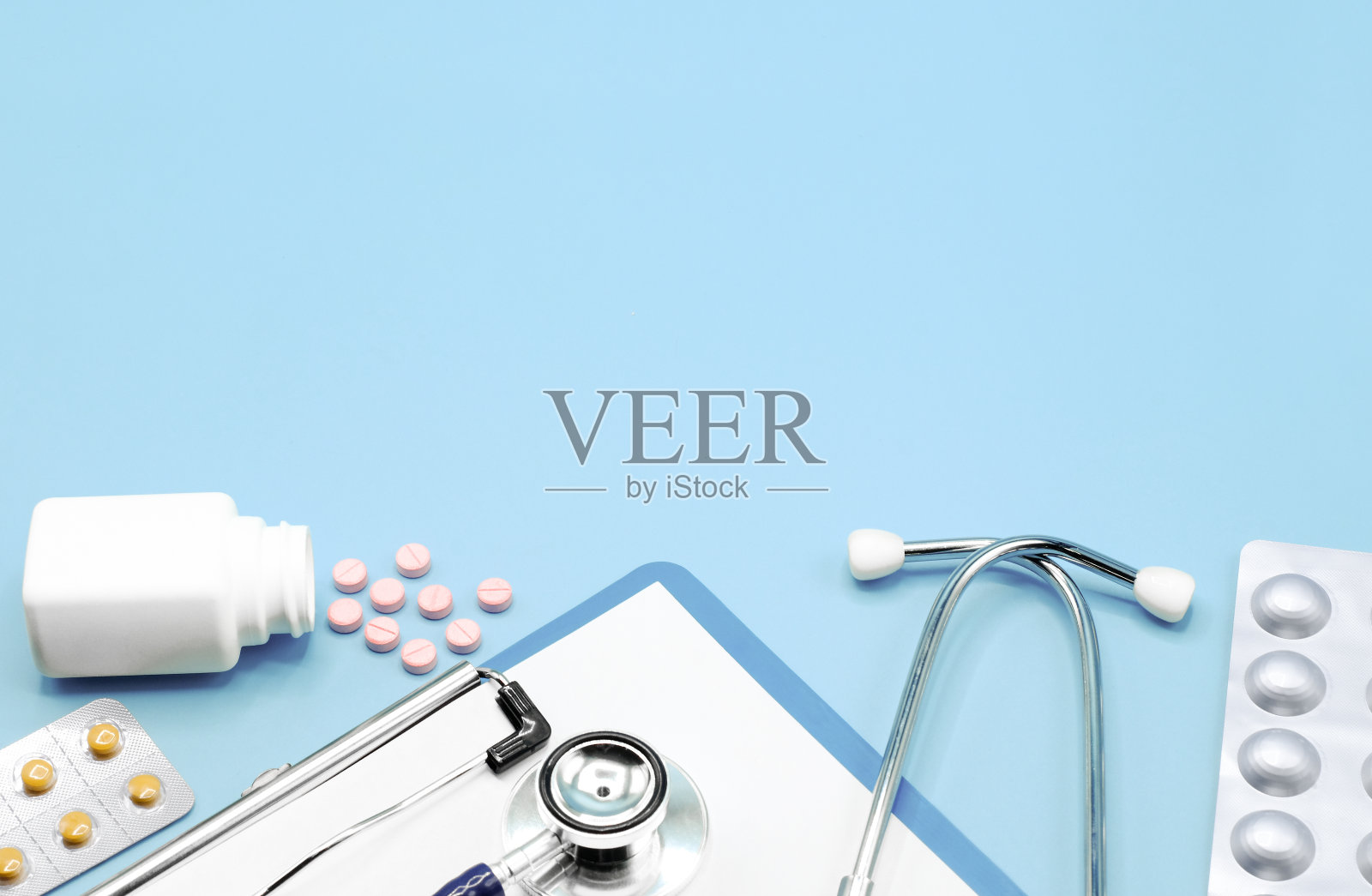 平坦的药片，药物，听诊器和书写垫回形针板，在浅蓝色的背景上拷贝空间，医疗保健和医疗概念，俯视图照片。照片摄影图片