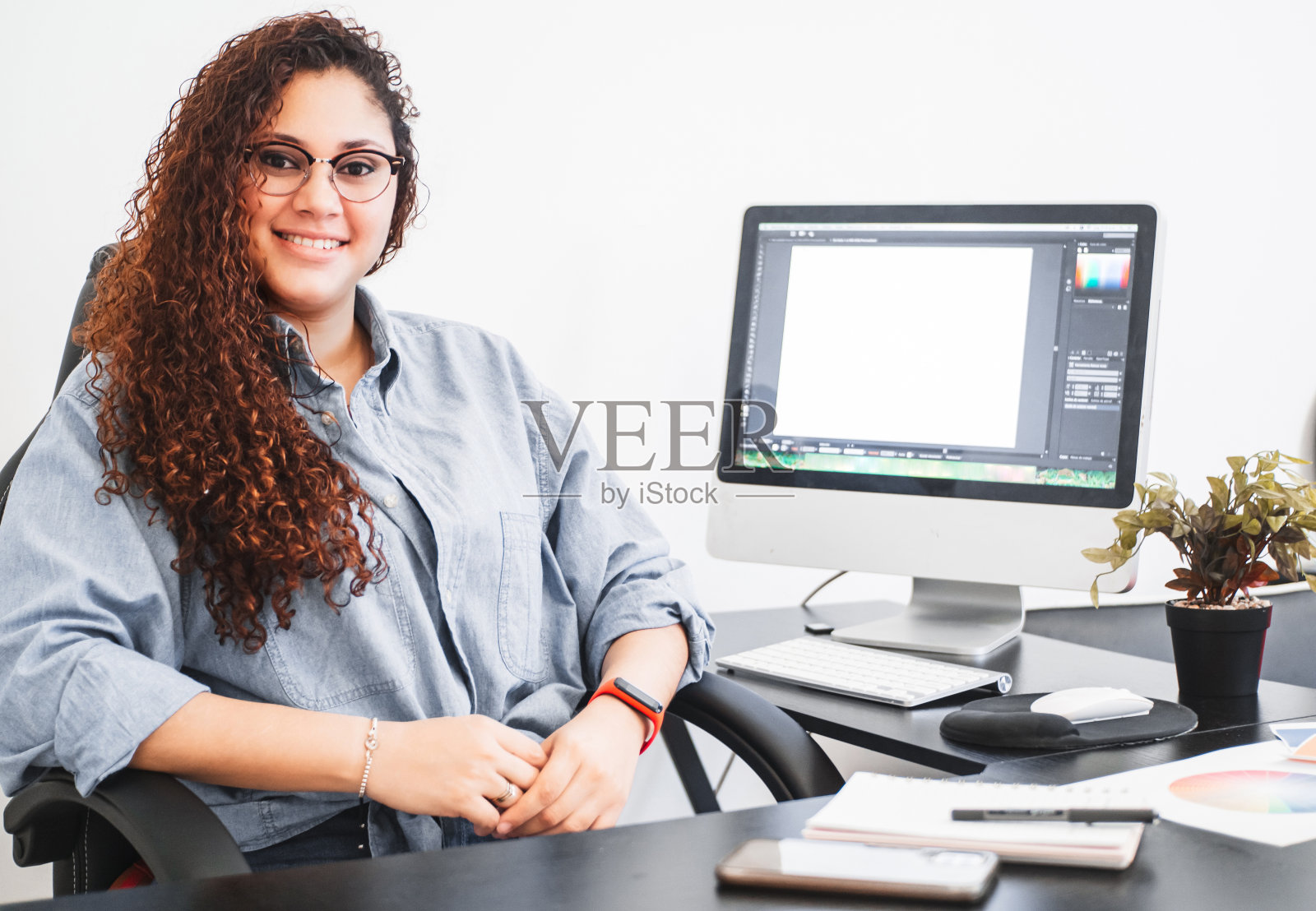 一位年轻的拉丁美洲平面设计师坐在办公室里的肖像。照片摄影图片