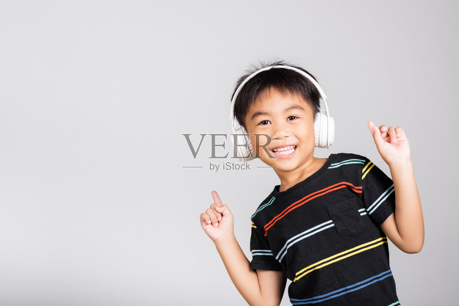 5-6岁的小男孩戴着无线耳机听音乐照片摄影图片