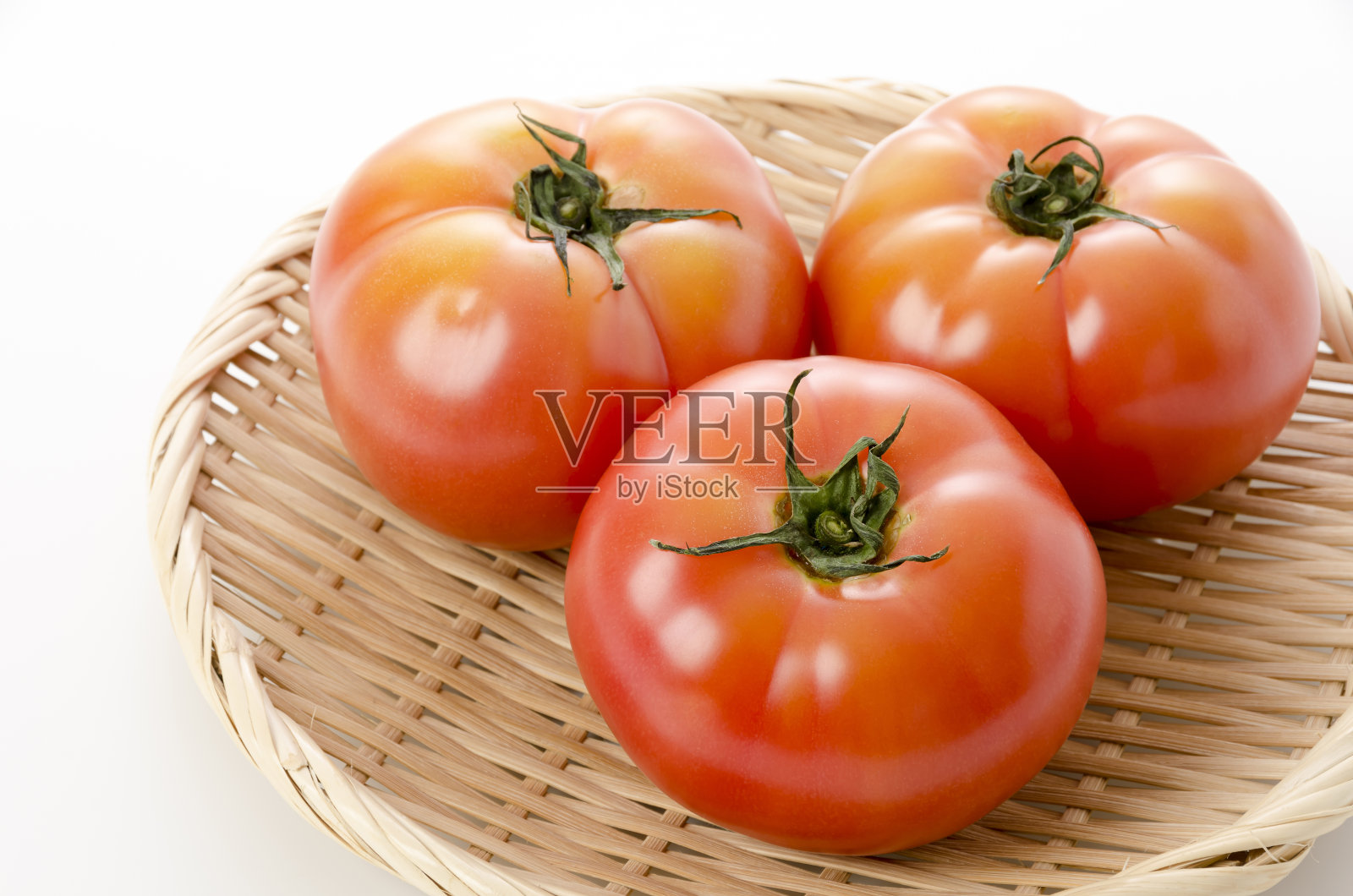 将成熟的红番茄放在白底竹筛上照片摄影图片