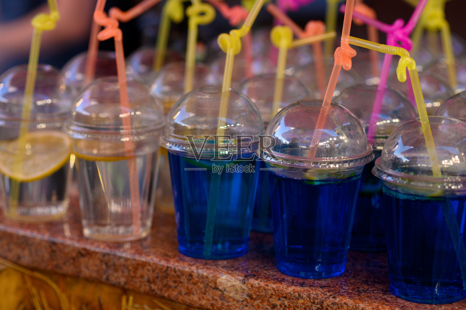 不同颜色的冷水在塑料杯。照片摄影图片