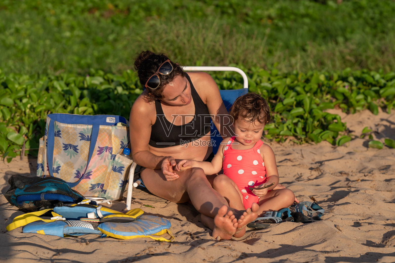 蹒跚学步的小女孩在沙滩上和妈妈玩耍照片摄影图片