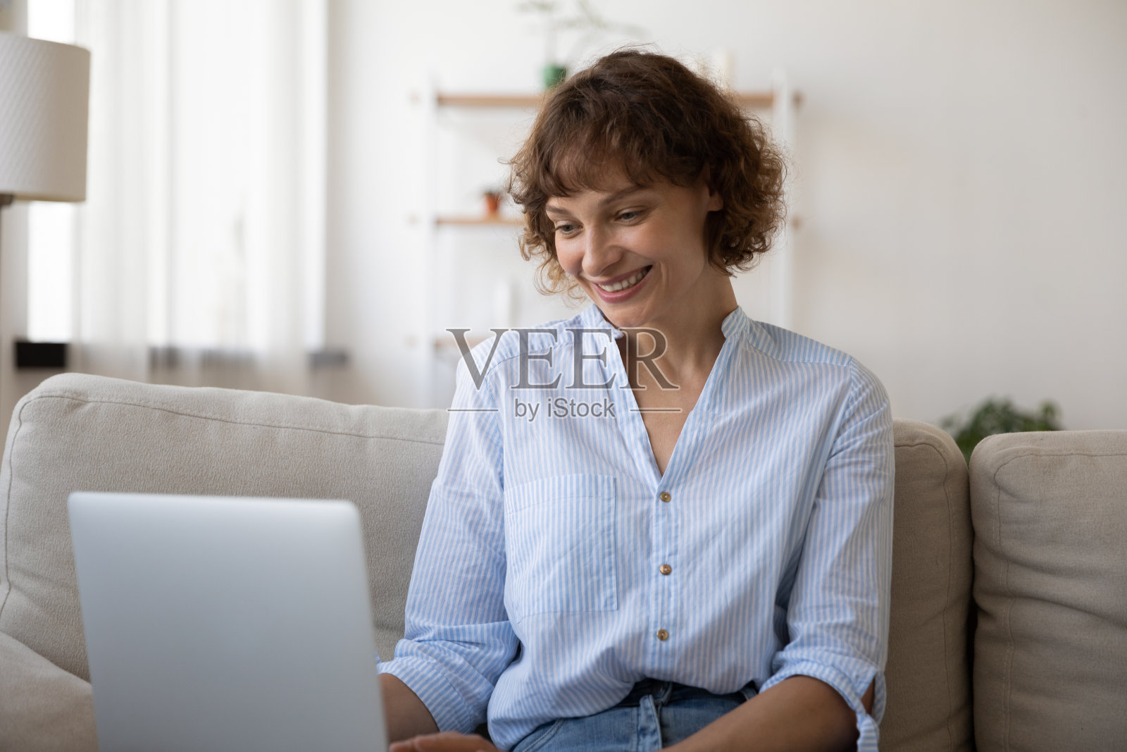 微笑着放松的40岁年轻女性使用笔记本电脑。照片摄影图片