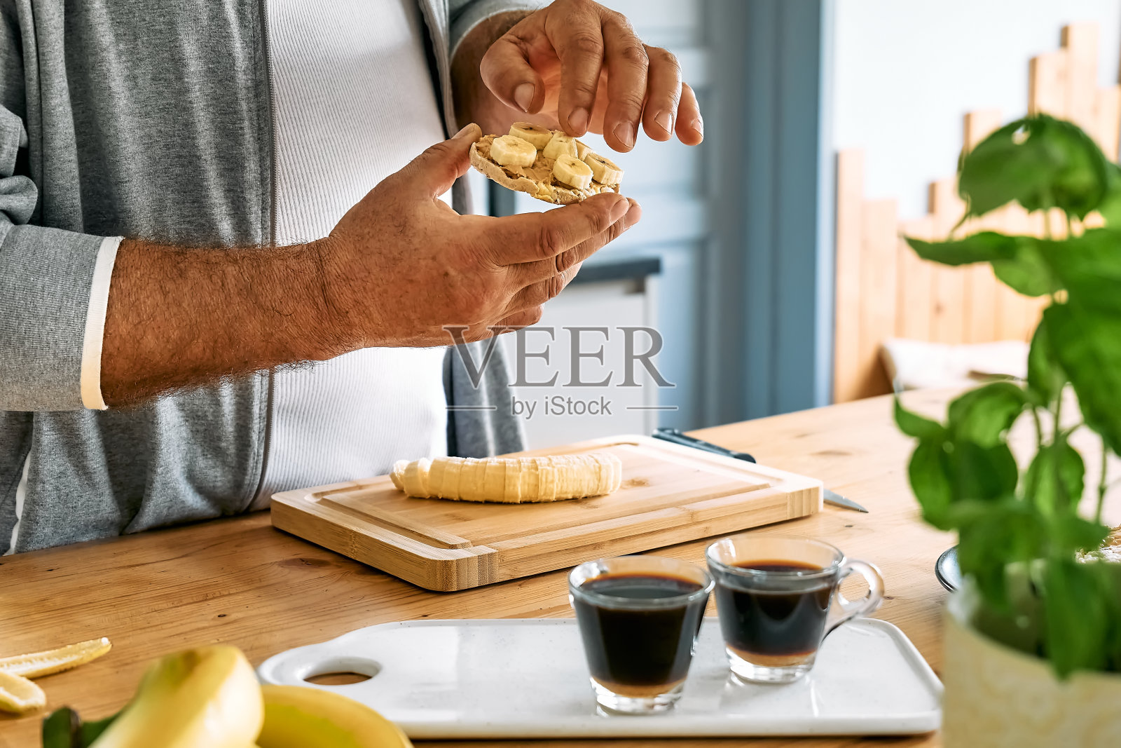 做健康早餐或早午餐的男人，把香蕉片放在膨化玉米蛋糕上，涂上花生酱。蛋白质饮食健康饮食理念。照片摄影图片