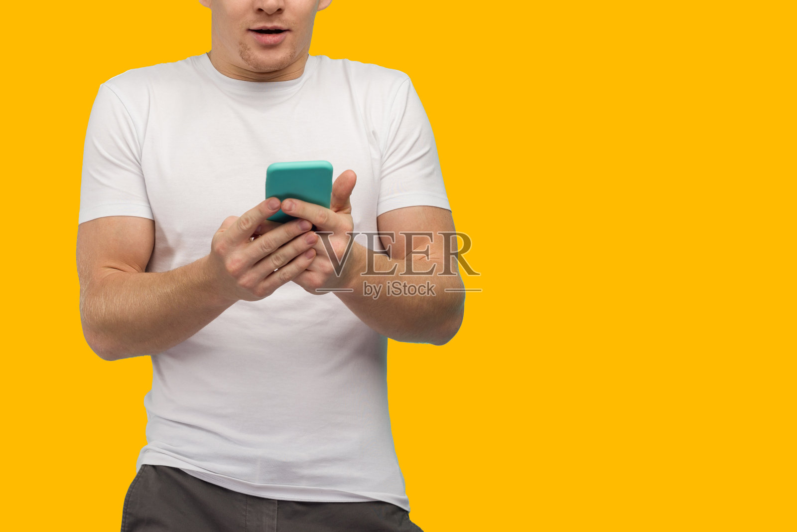 这位惊讶的体育迷在黄色背景的智能手机上收到了令人震惊的消息。照片摄影图片