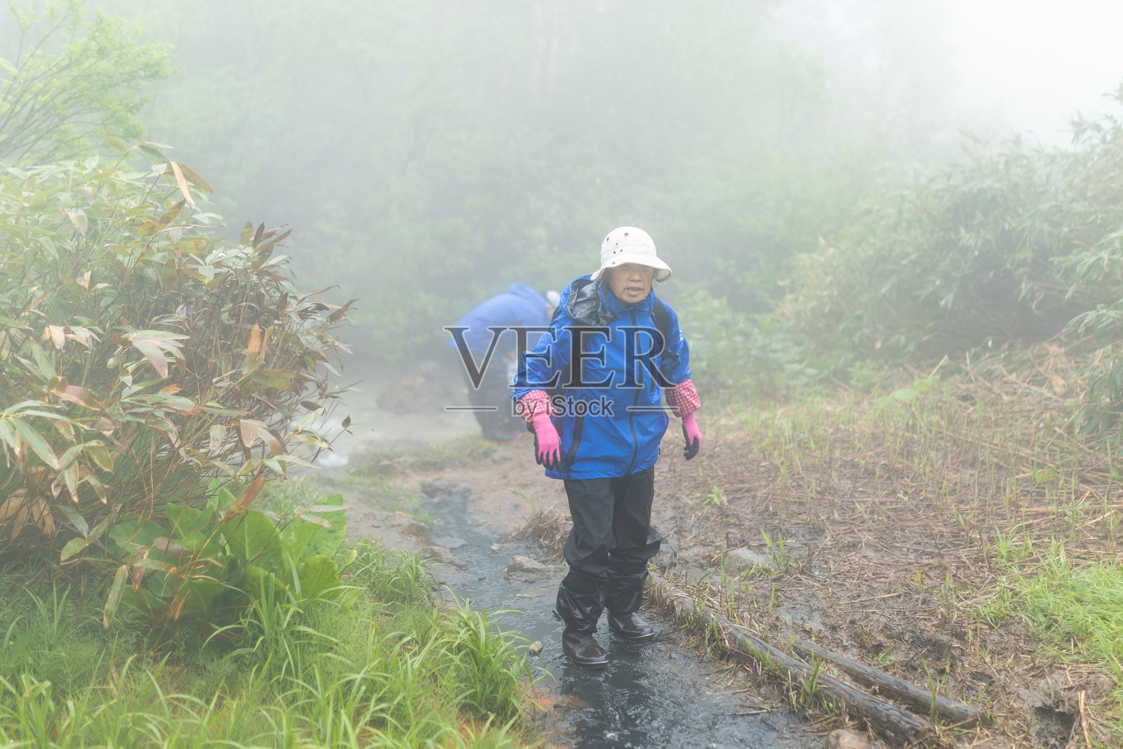 中年日本妇女走泥泞雾山路照片摄影图片