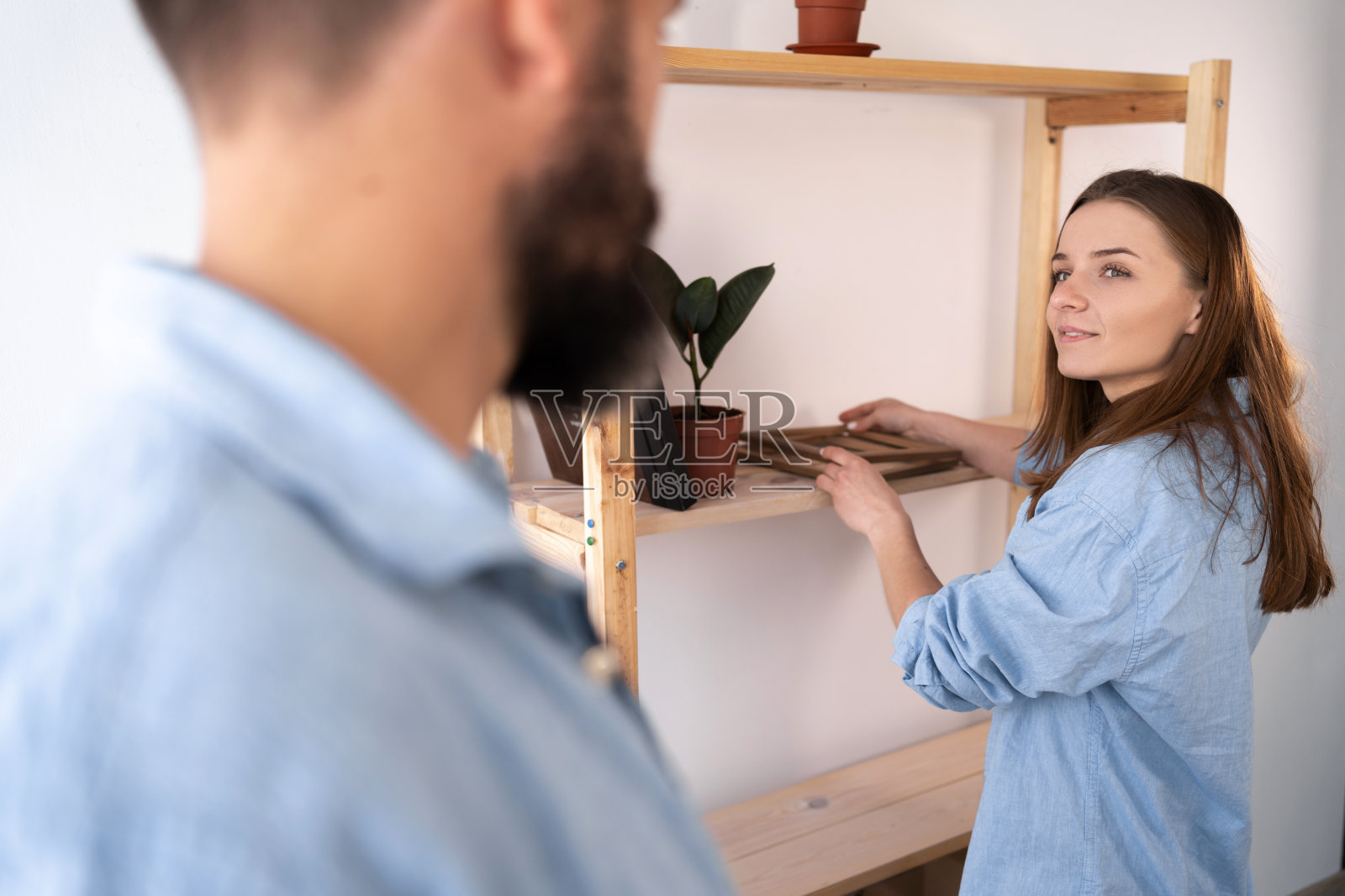 呆在家里，一起打扫公寓。男人和女人在客厅内部靠近架子，清洁架子照片摄影图片