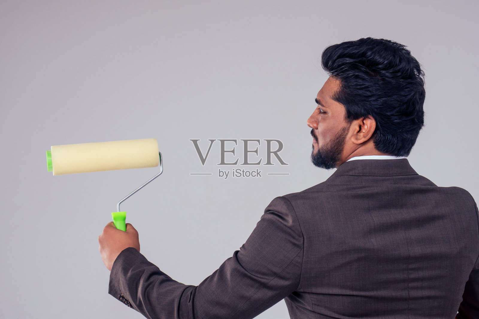 在工作室拷贝空间的白色背景上，年轻的商人手里拿着画笔照片摄影图片