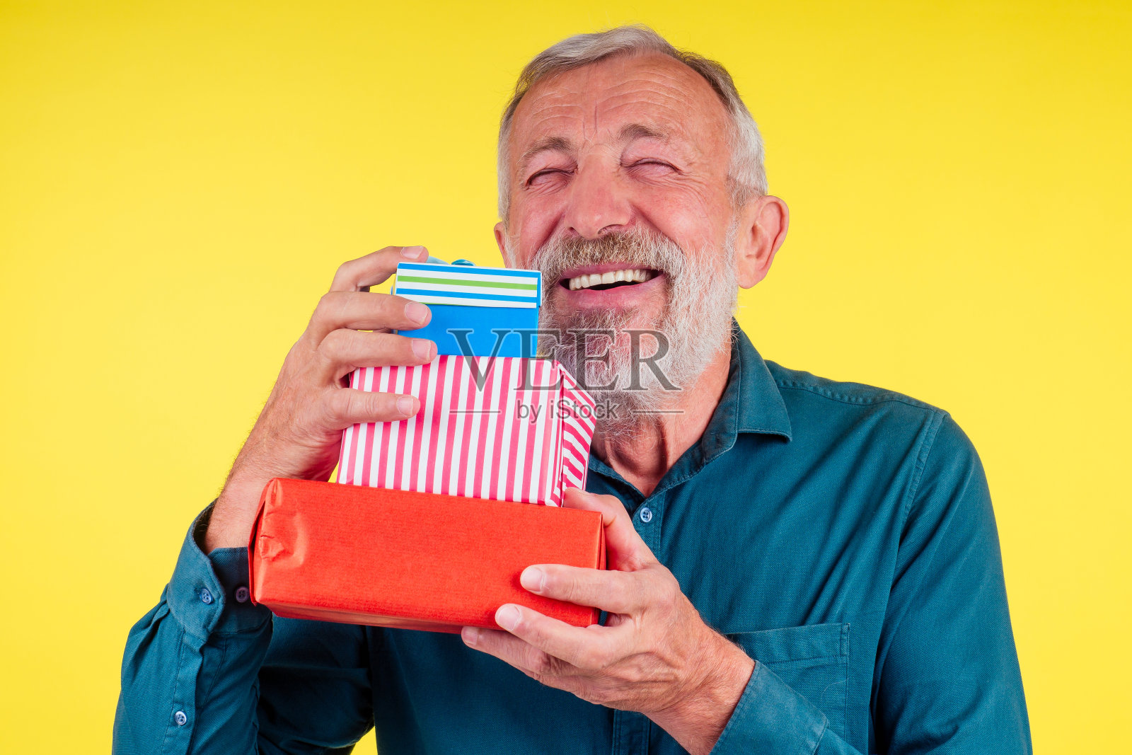 肖像惊讶的白人老人拿着两个盒子的礼物在工作室的黄色背景照片摄影图片