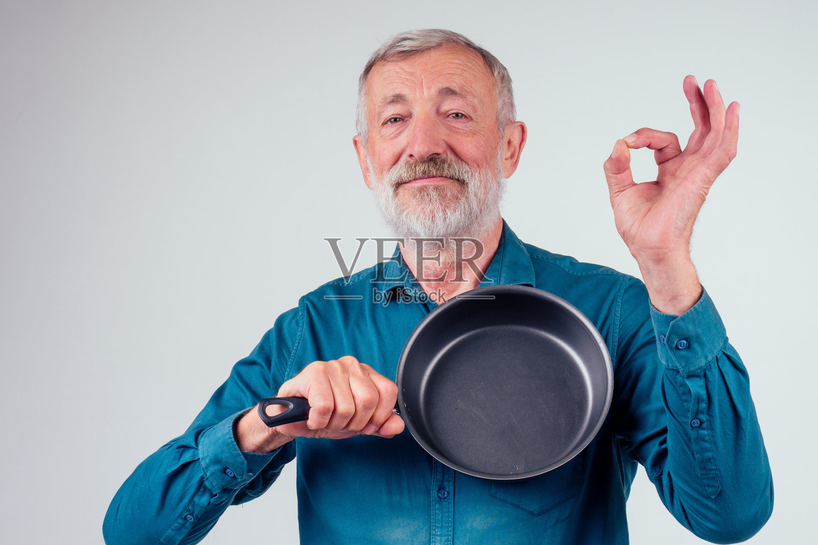 男子老持有油炸金属不粘锅在工作室白色背景照片摄影图片