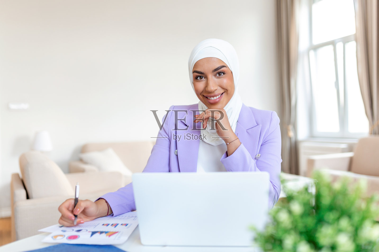 有吸引力的阿拉伯女性在笔记本电脑和书桌上的文件工作。阿拉伯女商人在家工作。奉献精神和技术。这对她完成任务至关重要照片摄影图片