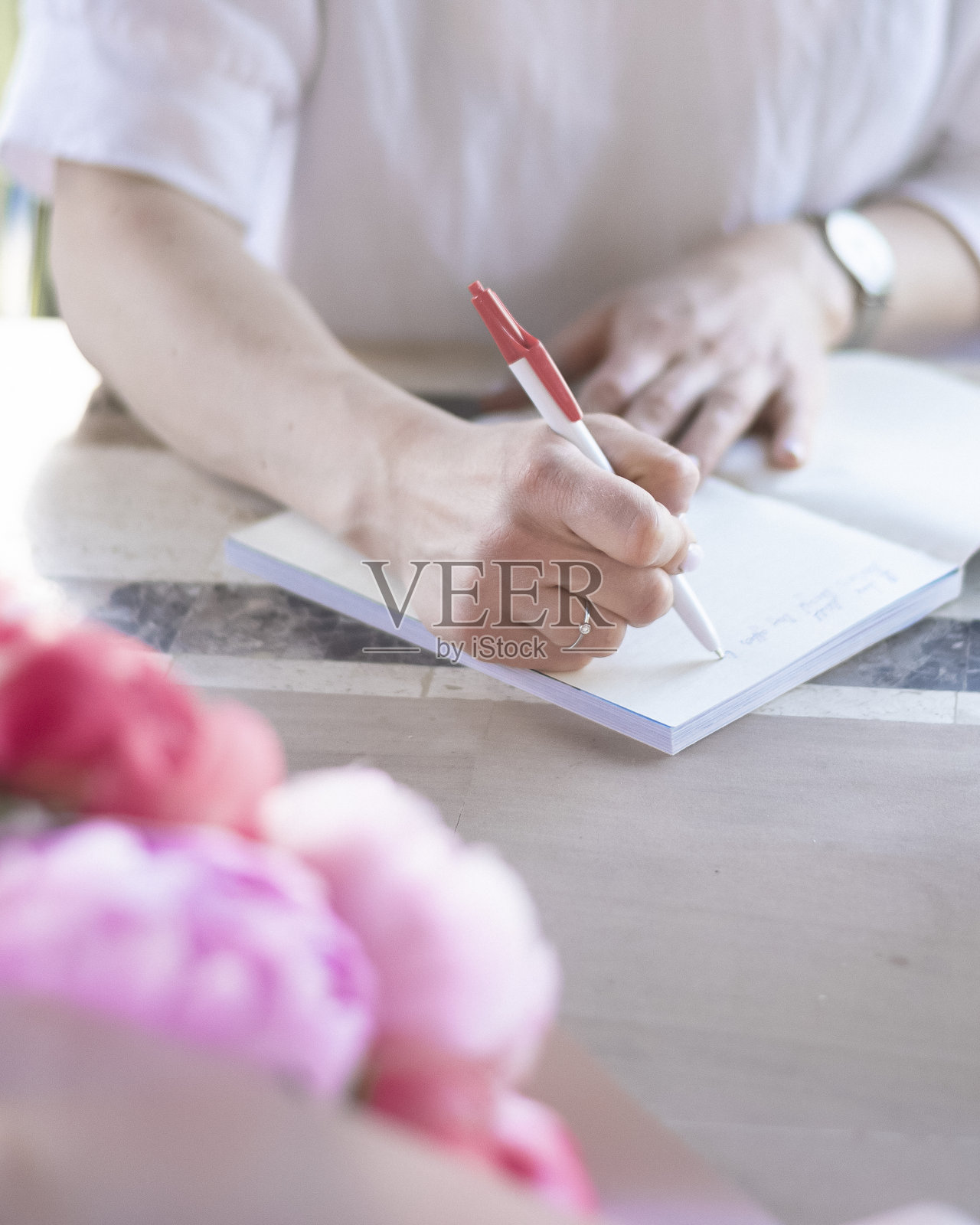 一个年轻的女人在笔记本上做笔记，写一个清单照片摄影图片