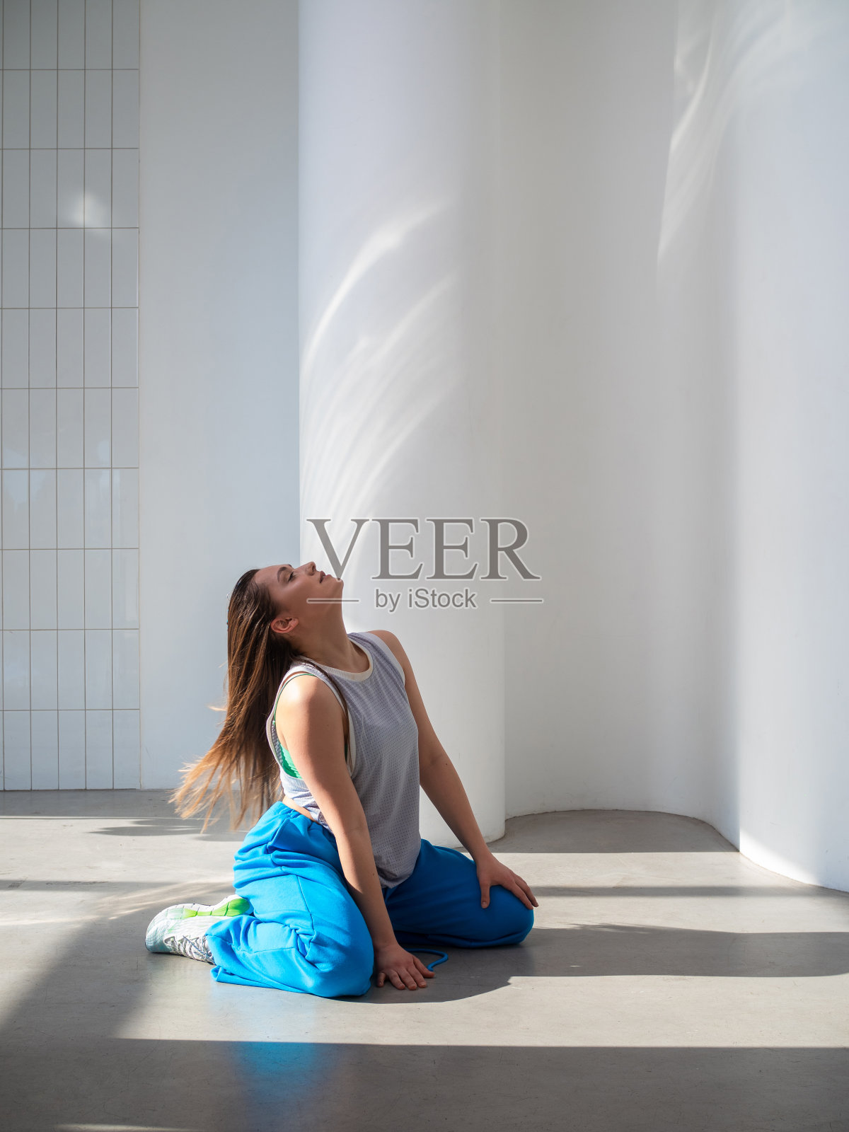 现代舞，时髦的黑发女郎穿着宽松的蓝色裤子，跳着爵士-放克舞。照片摄影图片