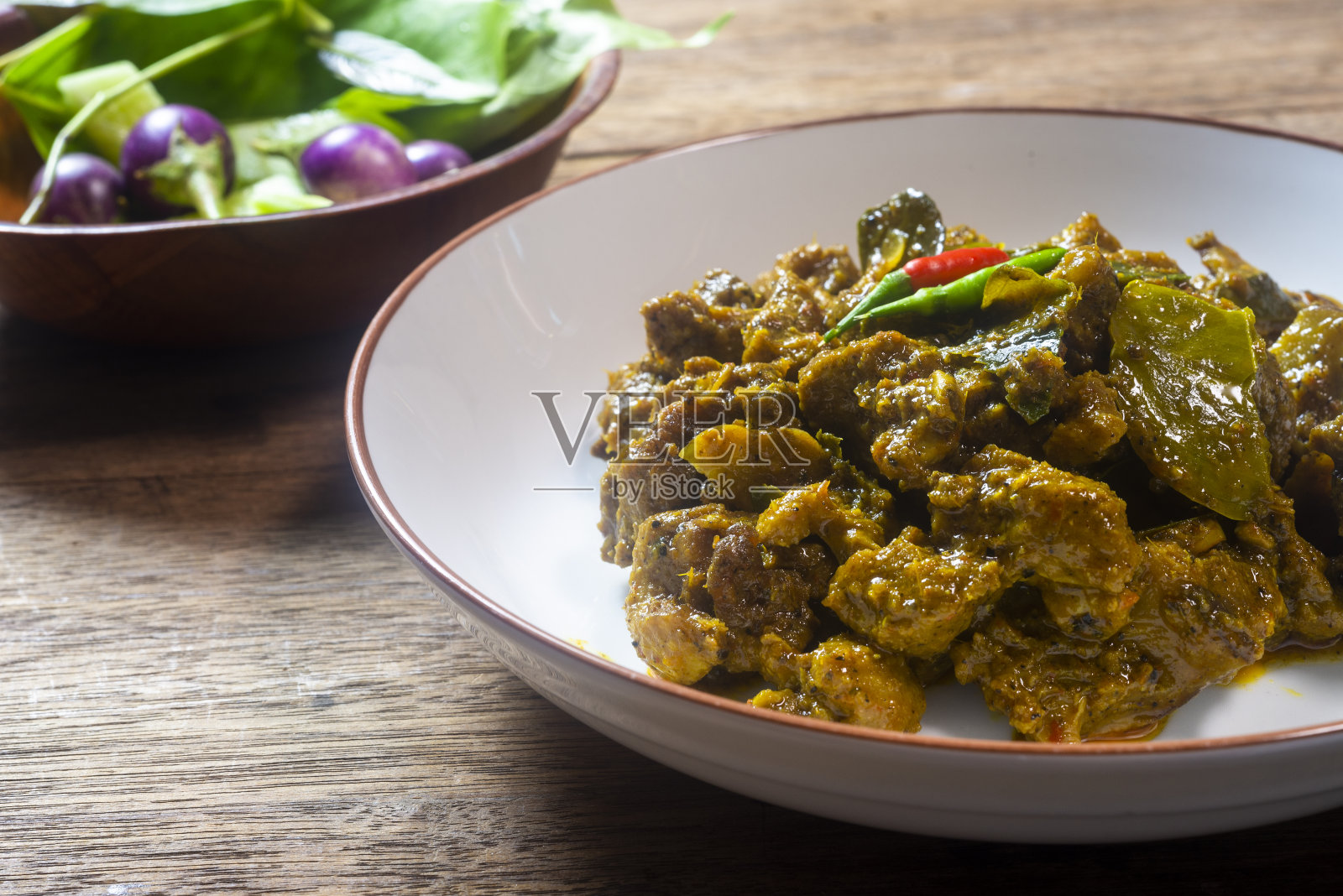 木桌上放着香辣咖喱鸭酱。可以吃了。照片摄影图片