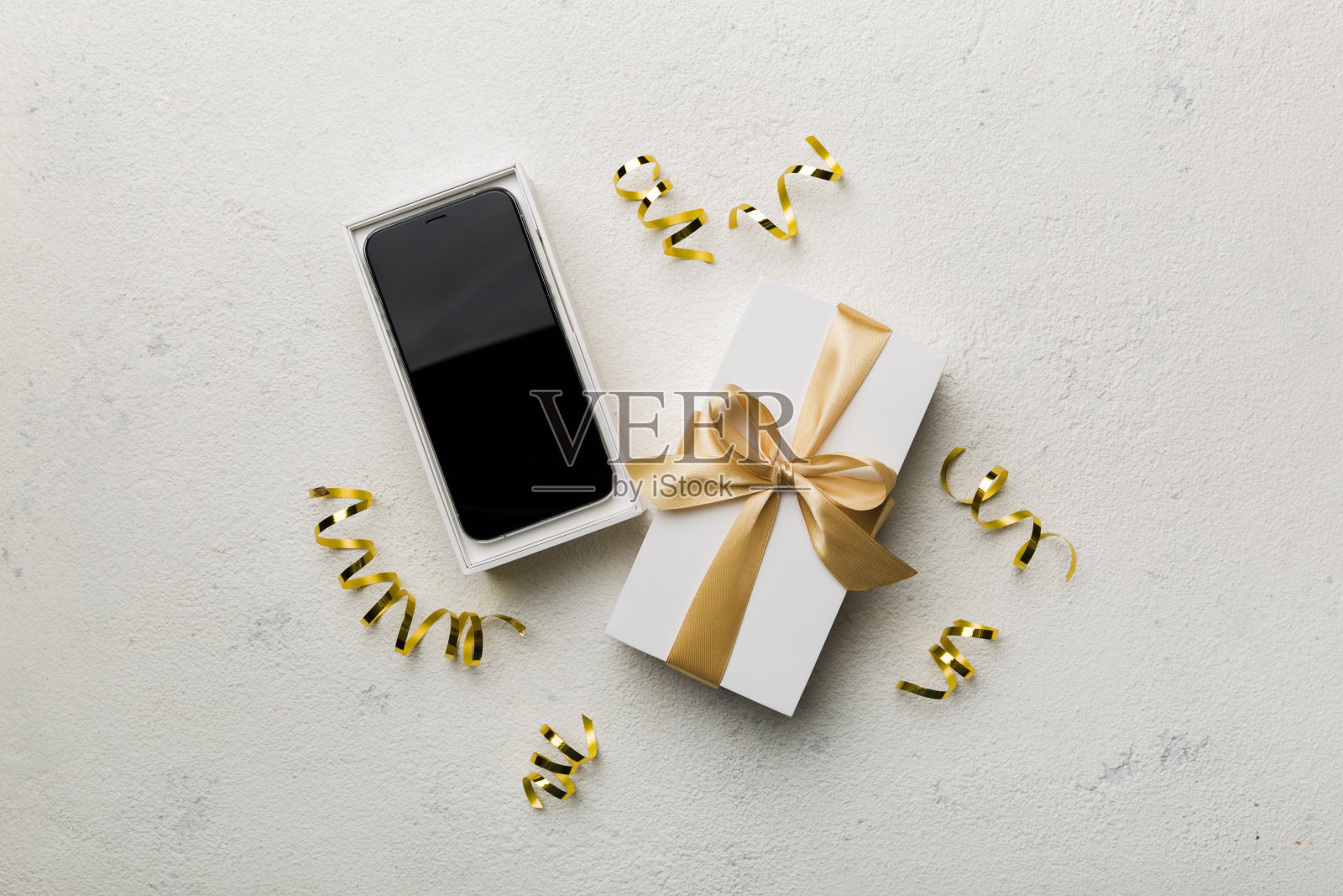 打开礼品盒，金色丝带和智能手机彩色背景，俯视图。空白开箱包装模型，模板为您的设计品牌模型照片摄影图片