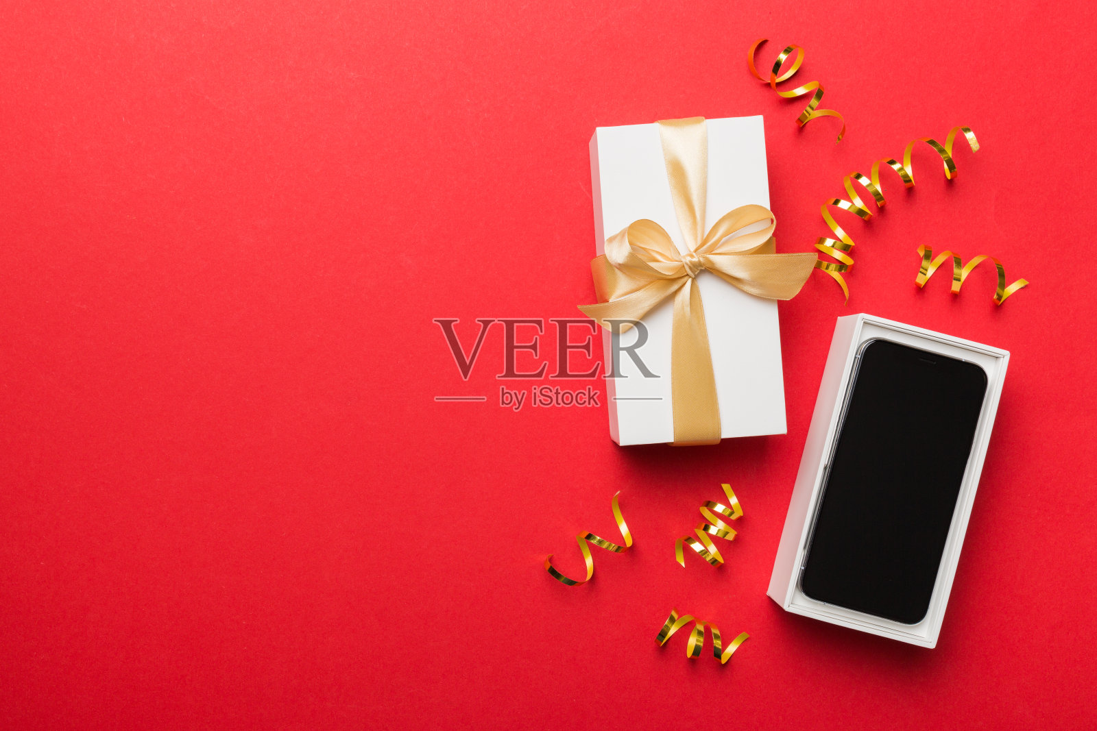 打开礼品盒，金色丝带和智能手机彩色背景，俯视图。空白开箱包装模型，模板为您的设计品牌模型照片摄影图片