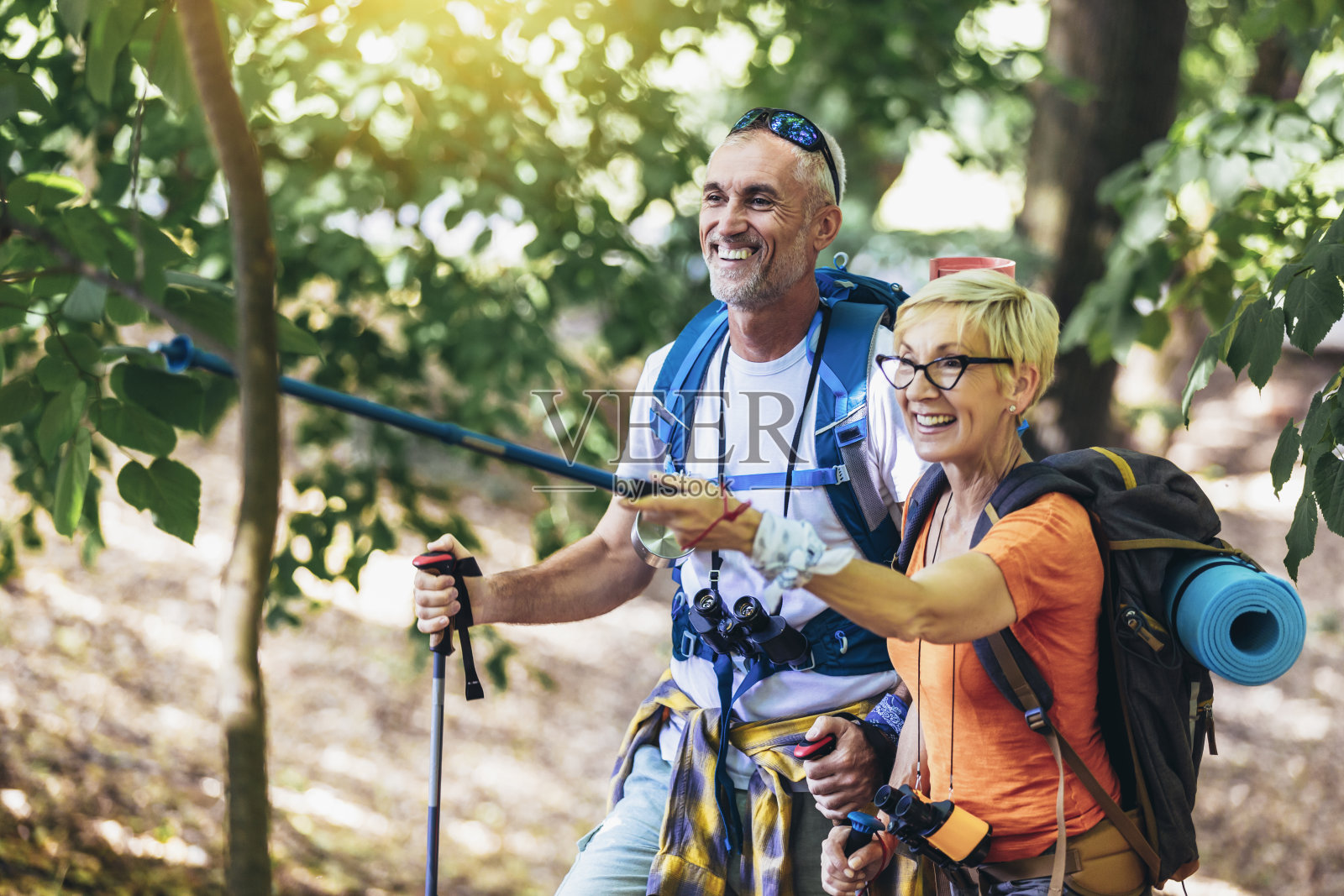 一对老夫妇背着背包和登山杖在森林里徒步旅行。照片摄影图片