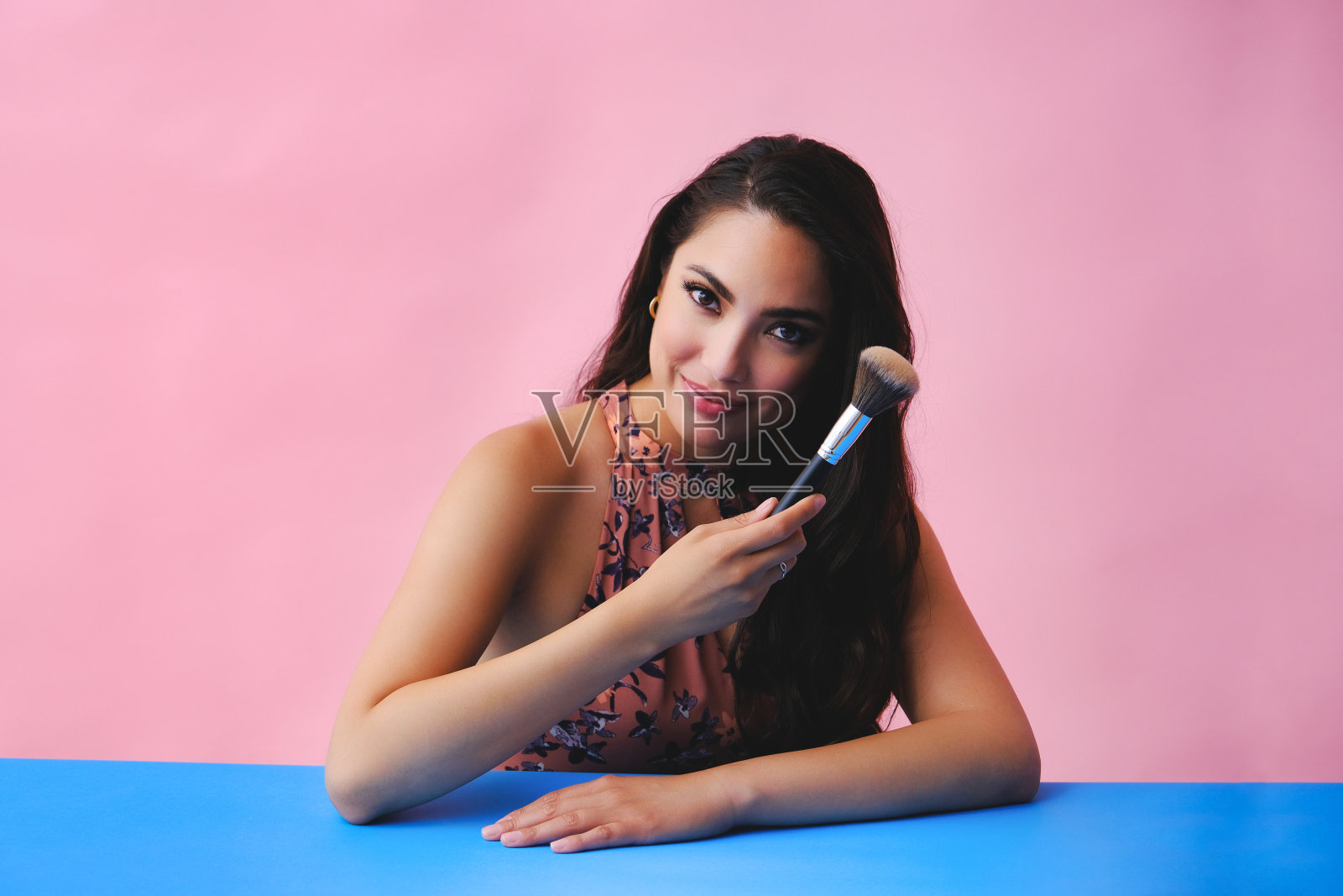 年轻的成年拉丁美女与化妆刷的工作室背景照片摄影图片