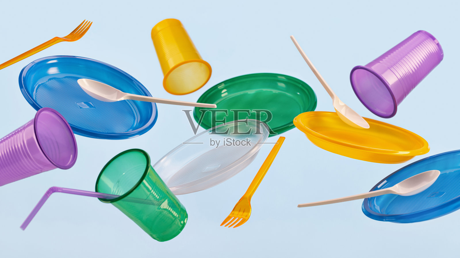 蓝色背景的彩色塑料餐具在空中飞舞。照片摄影图片