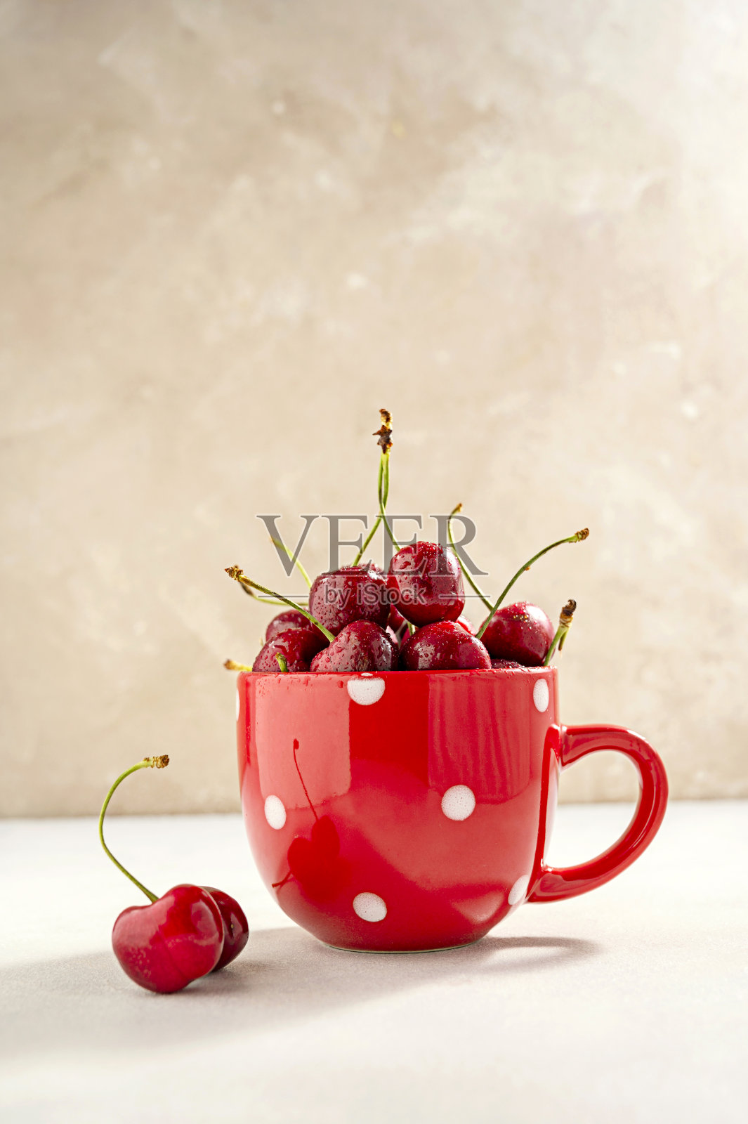 红色杯子里的新鲜红樱桃。夏天，时令水果美味可口。中性的背景。照片摄影图片