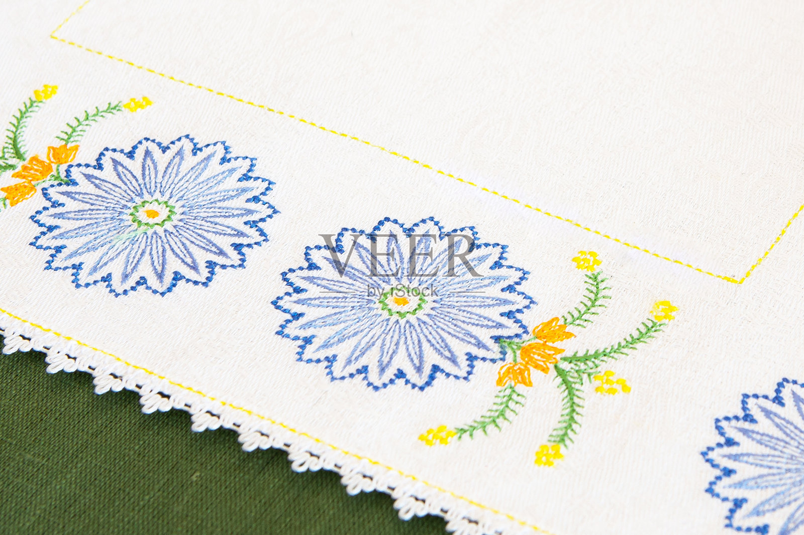 桌布上的刺绣细节，蓝色矢车菊的形式，在绿色的纹理背景。机器刺绣样品。照片摄影图片