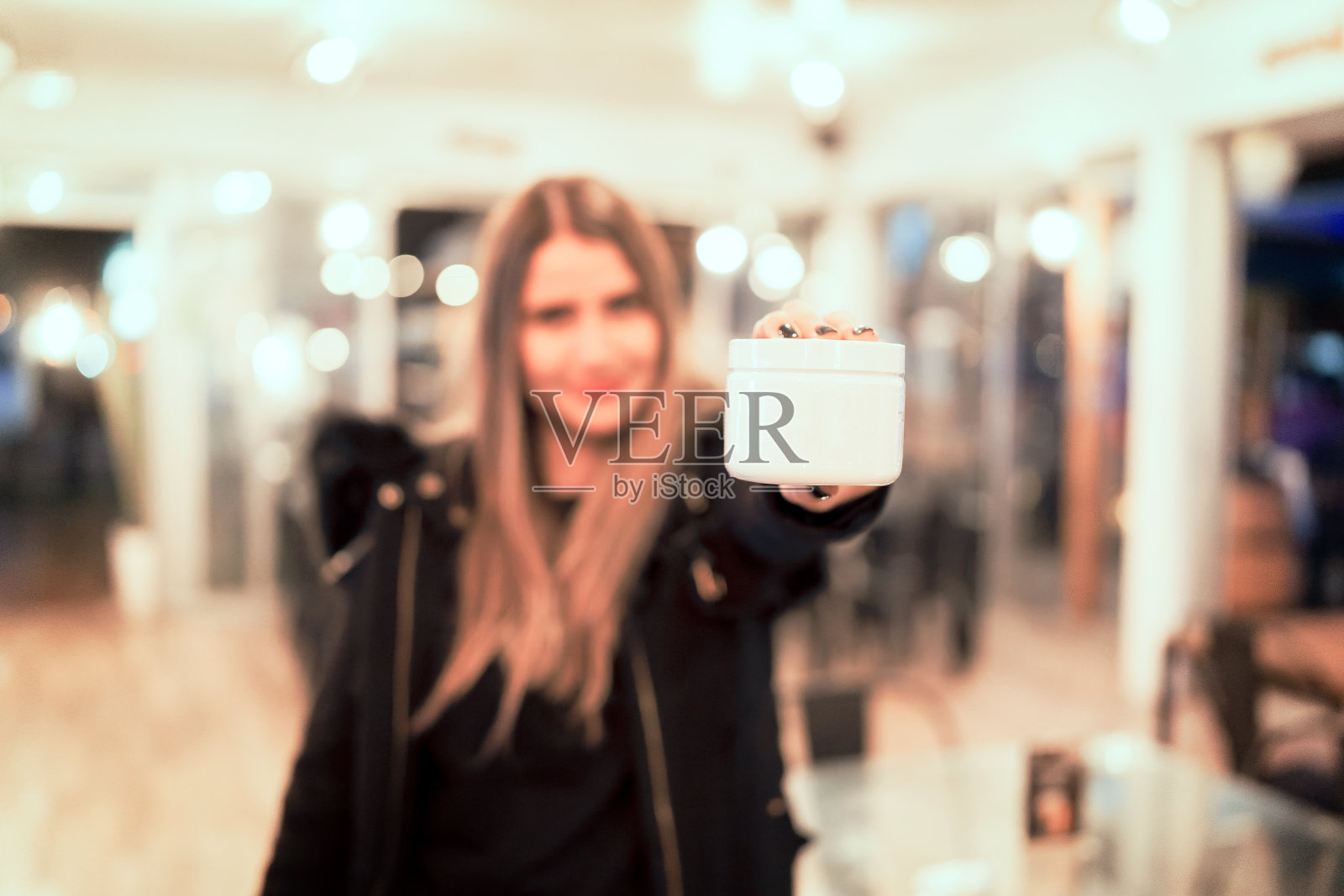 散焦美丽的女人持有霜或美丽的白色容器在她的手复制空间照片摄影图片