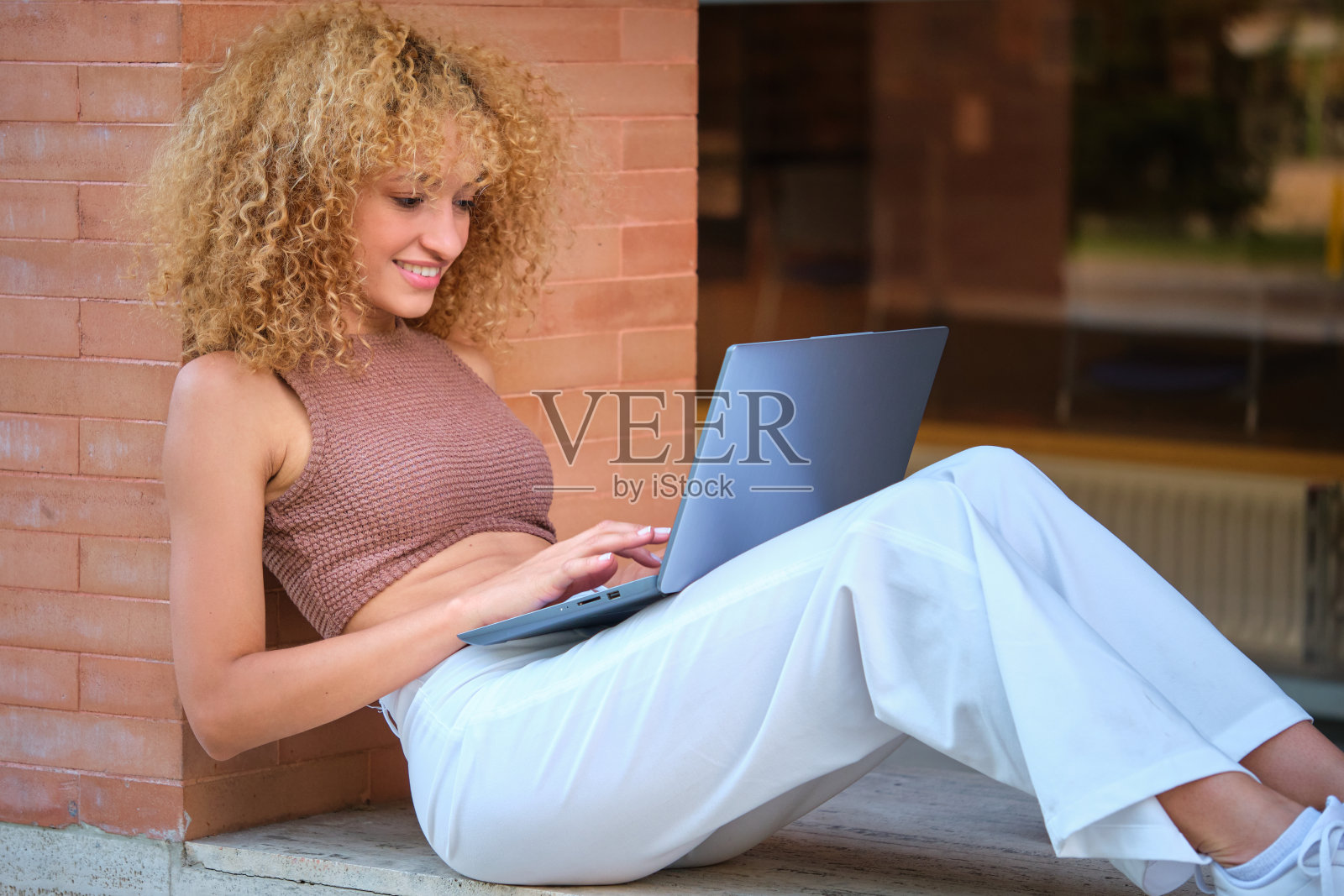 年轻的巴西学生，带着笔记本电脑和咖啡坐在校园里。照片摄影图片