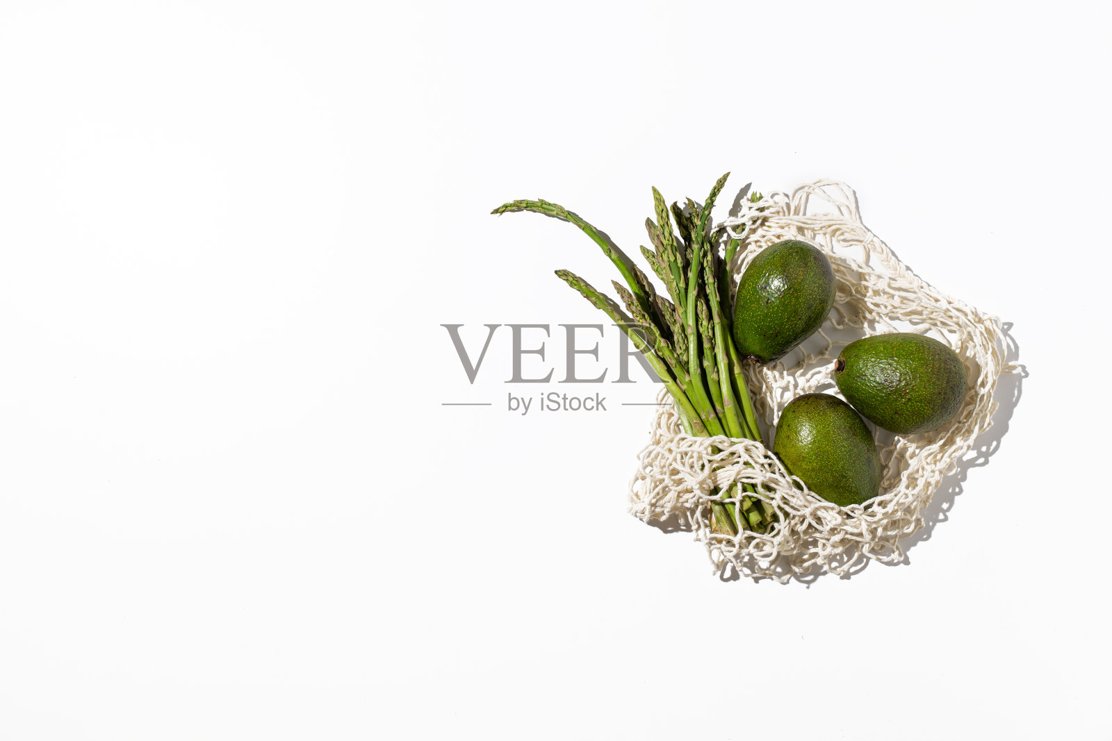 网眼生态可重复使用购物袋与有机蔬菜，水果和杂货在白色背景。照片摄影图片