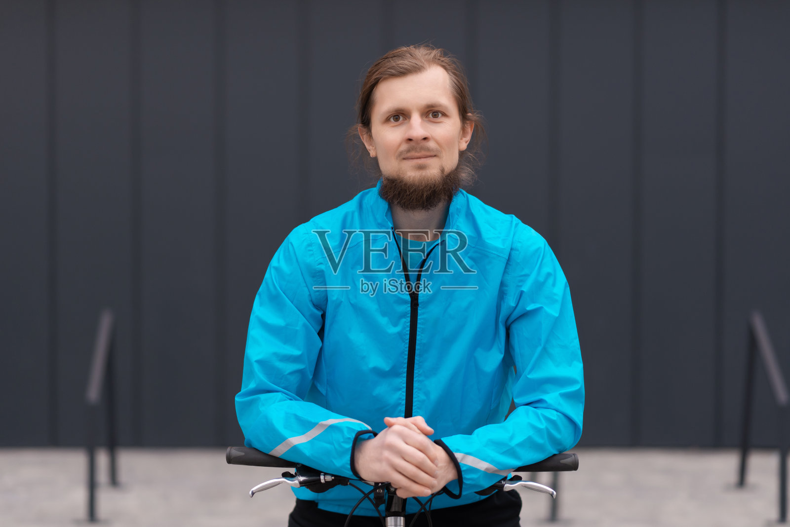 一个英俊的年轻人在一个阳光明媚的日子骑着自行车在城市里照片摄影图片