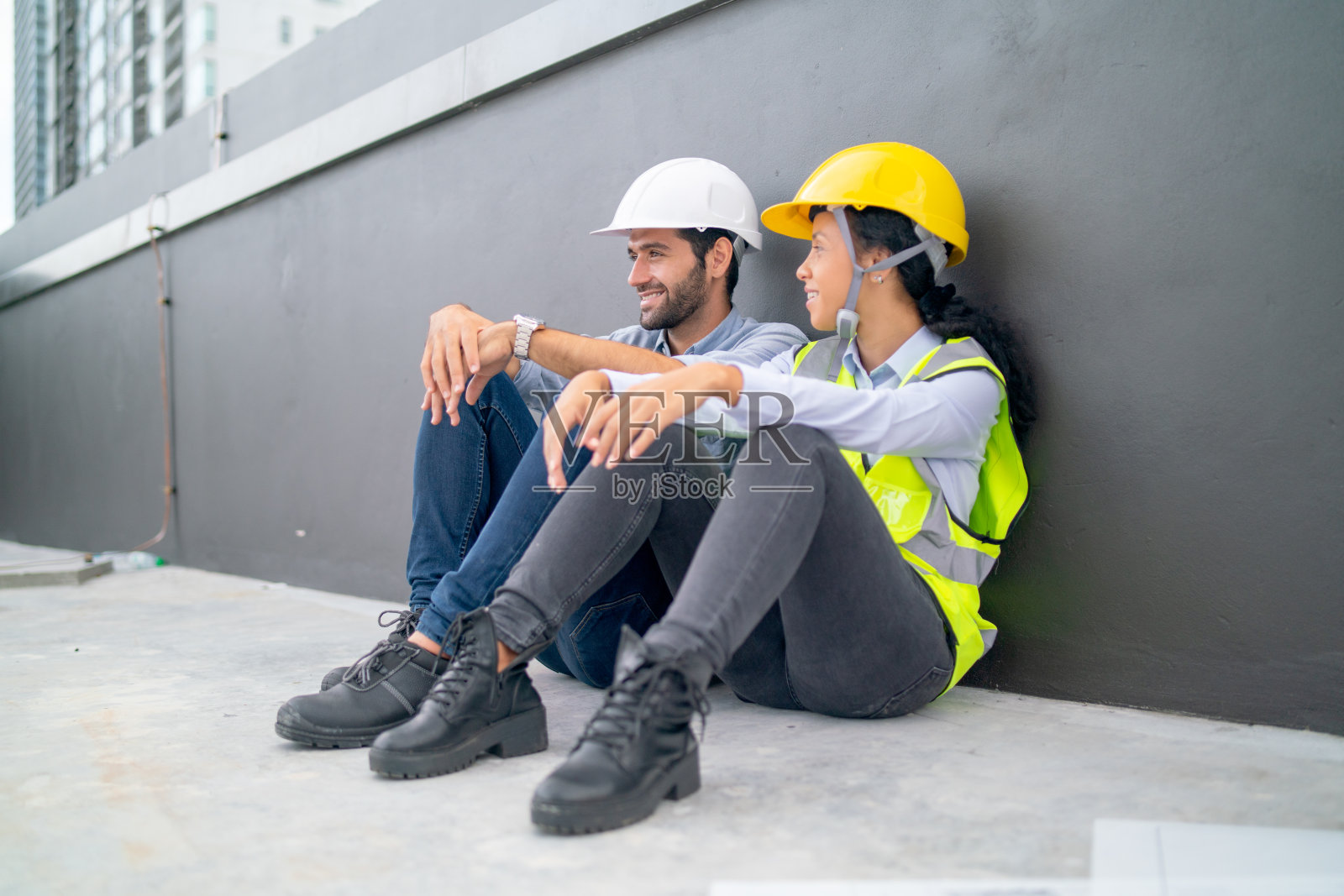 下班后，一对专业的工程师或技术员坐在工地露台的地板上休息，谈笑风生。照片摄影图片