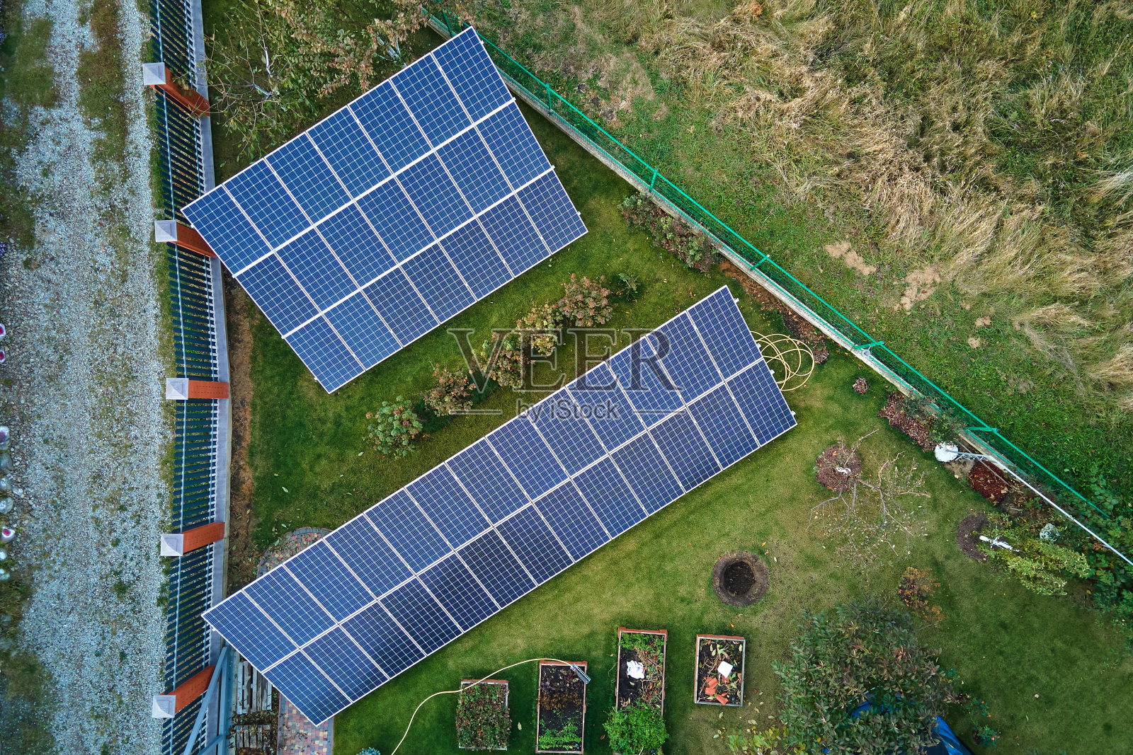 太阳能光伏板安装在后院地面的独立框架上，用于产生清洁的生态电能。自主住宅的概念照片摄影图片