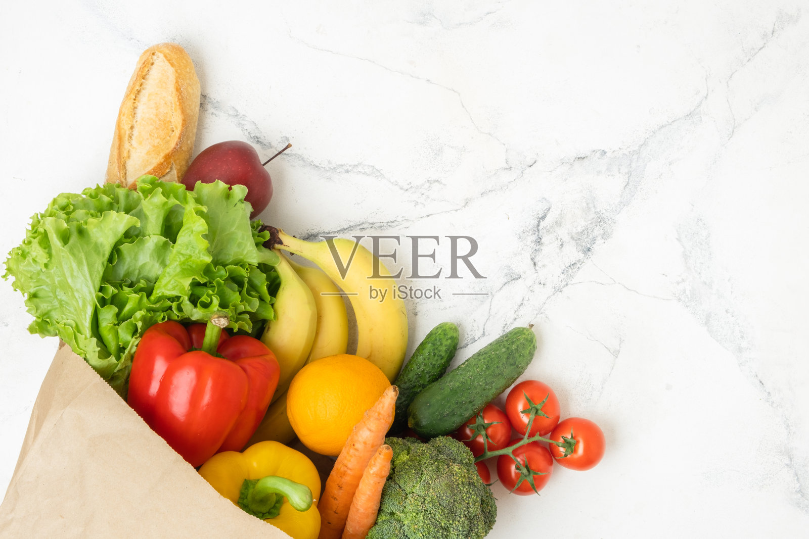 棕色纸袋装满了新鲜的水果和蔬菜在白色大理石背景。购物配送服务理念。健康饮食理念。自由空间。平躺照片摄影图片