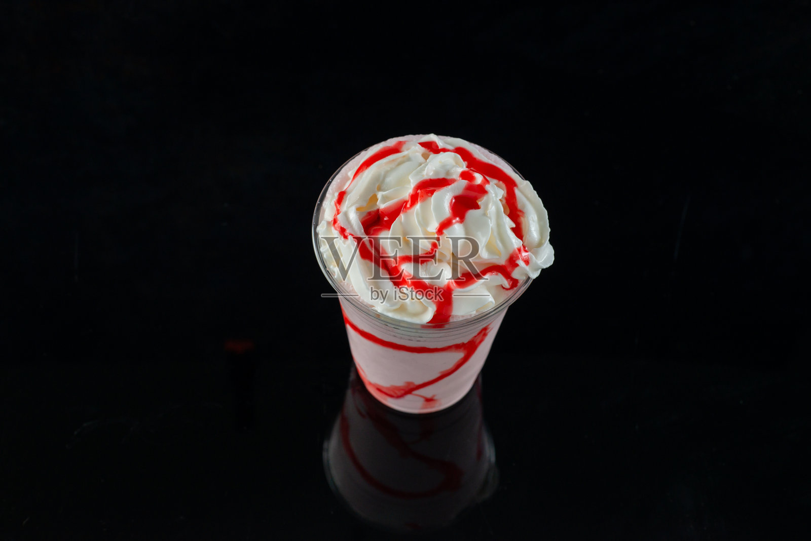 草莓奶昔与草莓糖浆在透明玻璃在黑暗的背景。照片摄影图片