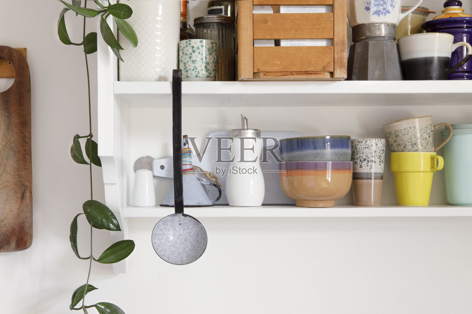 复古风格的厨房木制货架与厨房用具。储物柜是开放式的，厨房的架子上放着陶瓷陶器。一套色彩鲜艳的盘子在现代室内，家居装饰。照片摄影图片