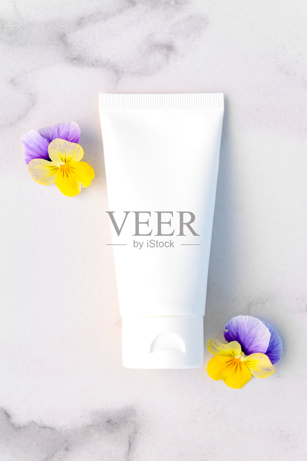 模拟白色挤压瓶化妆品霜管药品或化妆品品牌-洗发水，凝胶，护肤品。润肤霜空白瓶和大理石背景的三色堇花。前视图。照片摄影图片