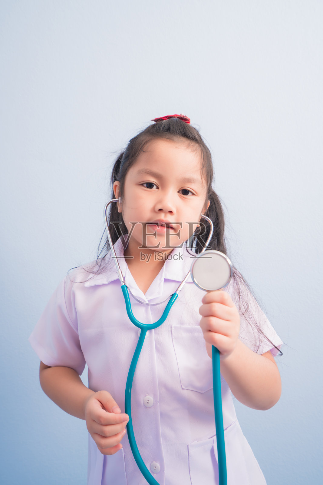 快乐可爱的女孩们穿着白色的医疗制服，脖子上戴着听诊器，像个医生。孩子梦想成为一名医生的职业概念照片摄影图片