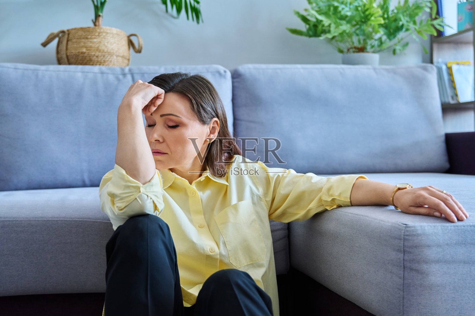 坐在沙发附近地板上的中年悲伤女子照片摄影图片