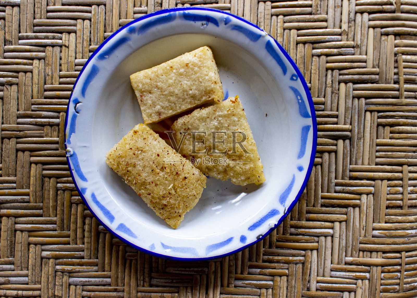 jadah goreng或油炸糯米糕装在搪瓷盘子里。木头背景照片摄影图片