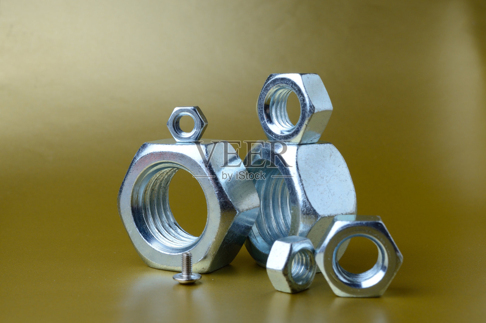 在黄色背景上组成不同尺寸的新螺母和螺栓。照片摄影图片