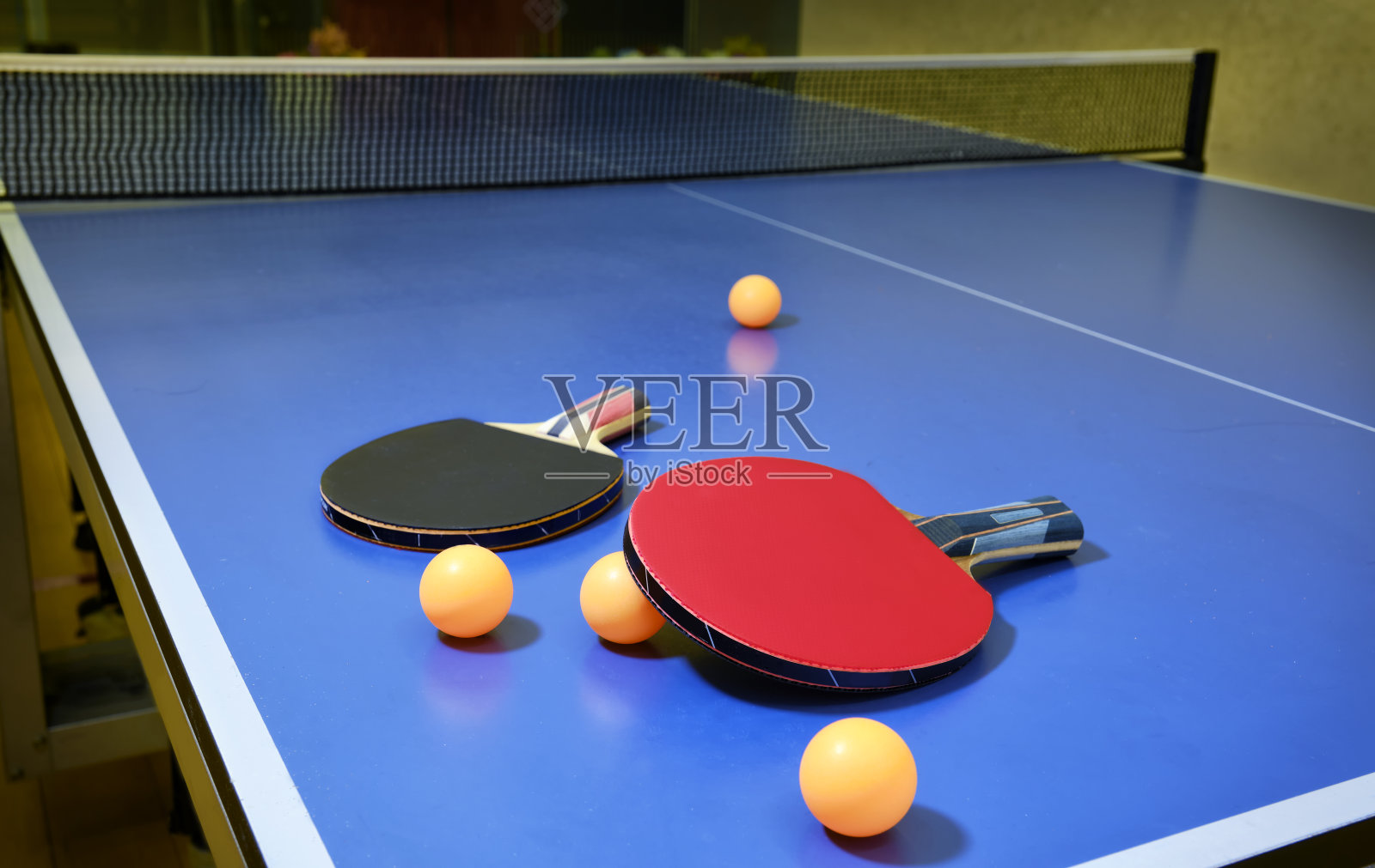 乒乓球，乒乓球，球拍和橙色的乒乓球放在蓝色的桌子上。照片摄影图片