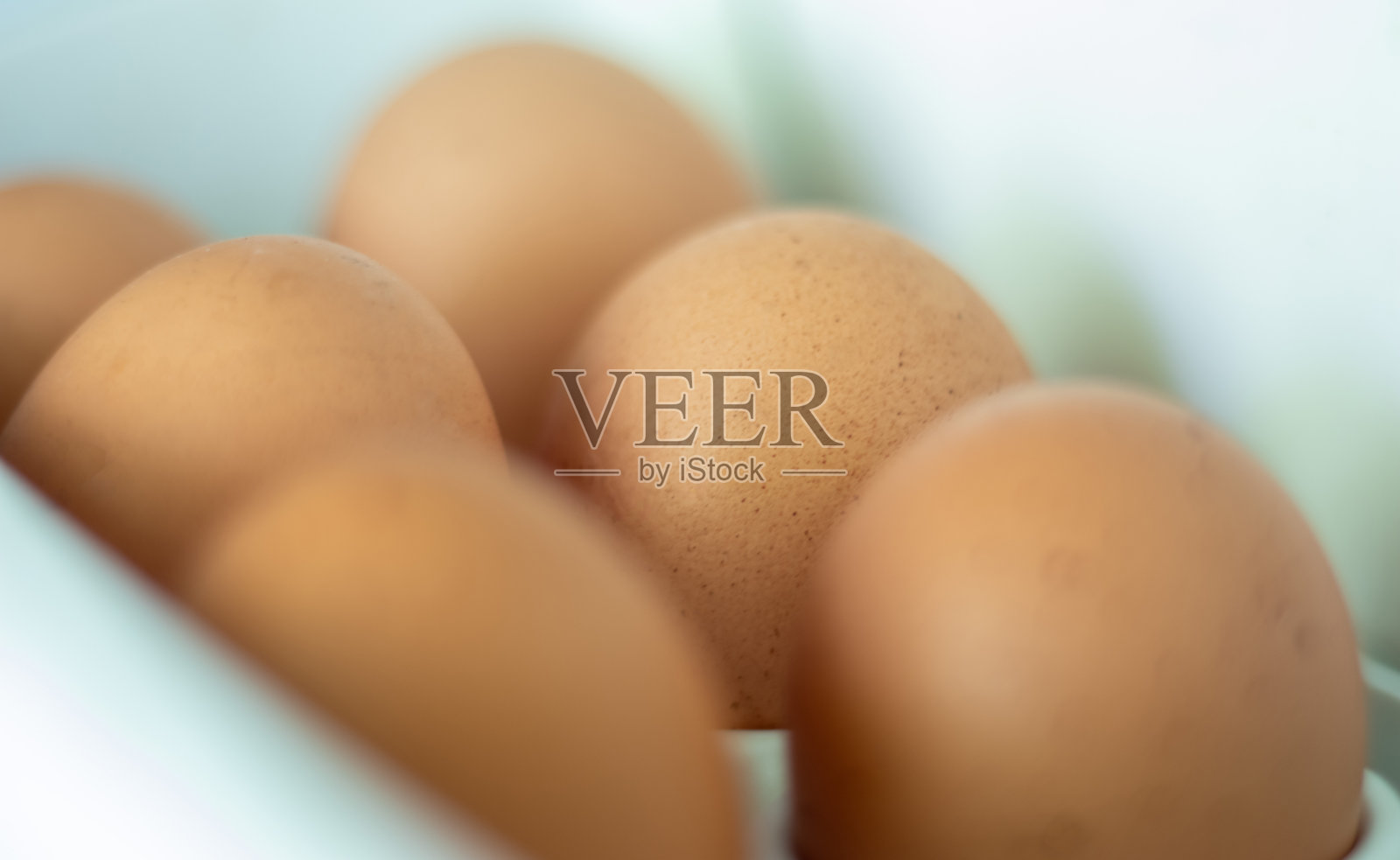 冰箱里的生鸡蛋，特写镜头。在冰箱门上的架子上用鸡蛋布裹着棕色的鸡蛋。选择的重点。照片摄影图片