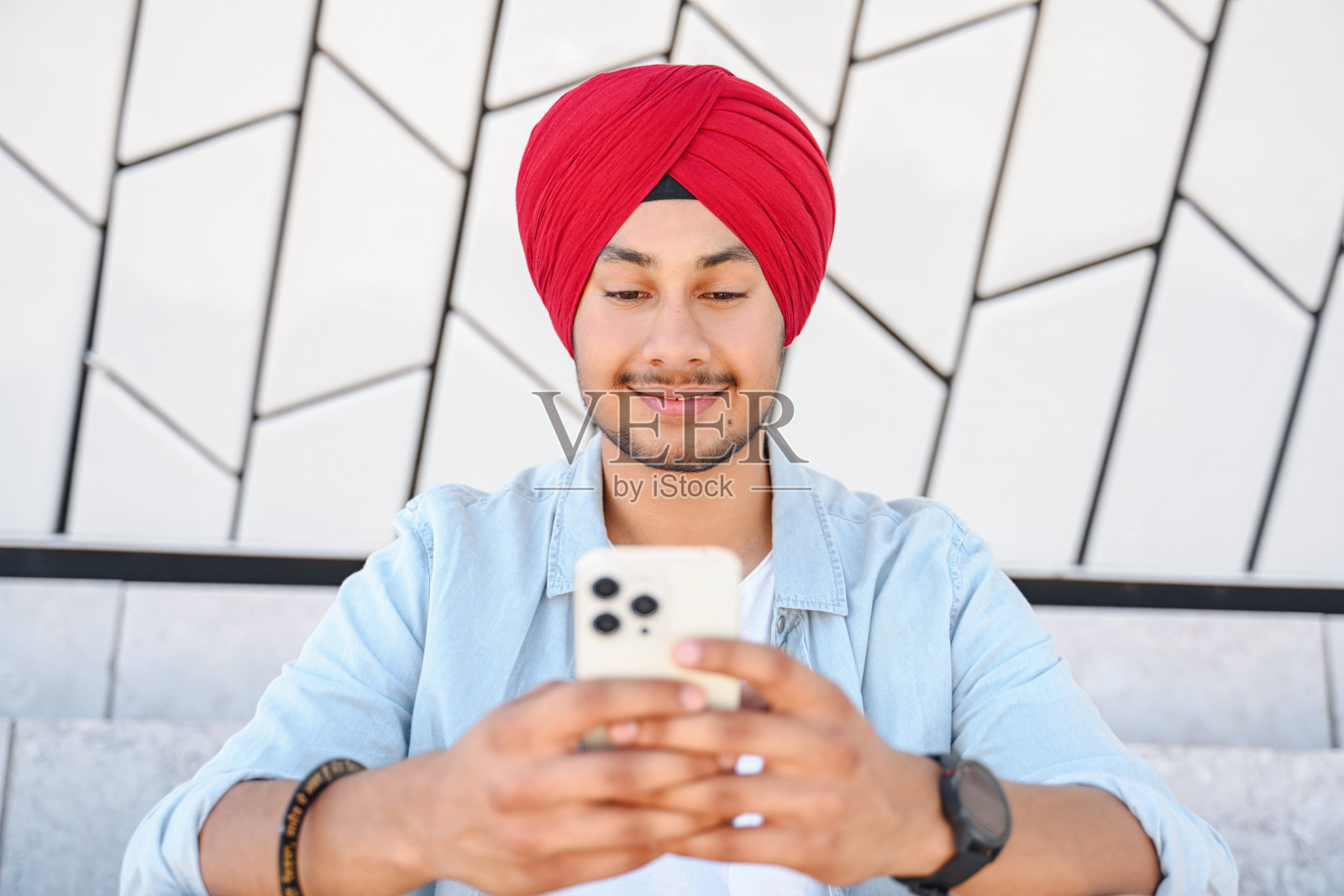 欢快的印度年轻人在户外用手机发信息的肖像。照片摄影图片