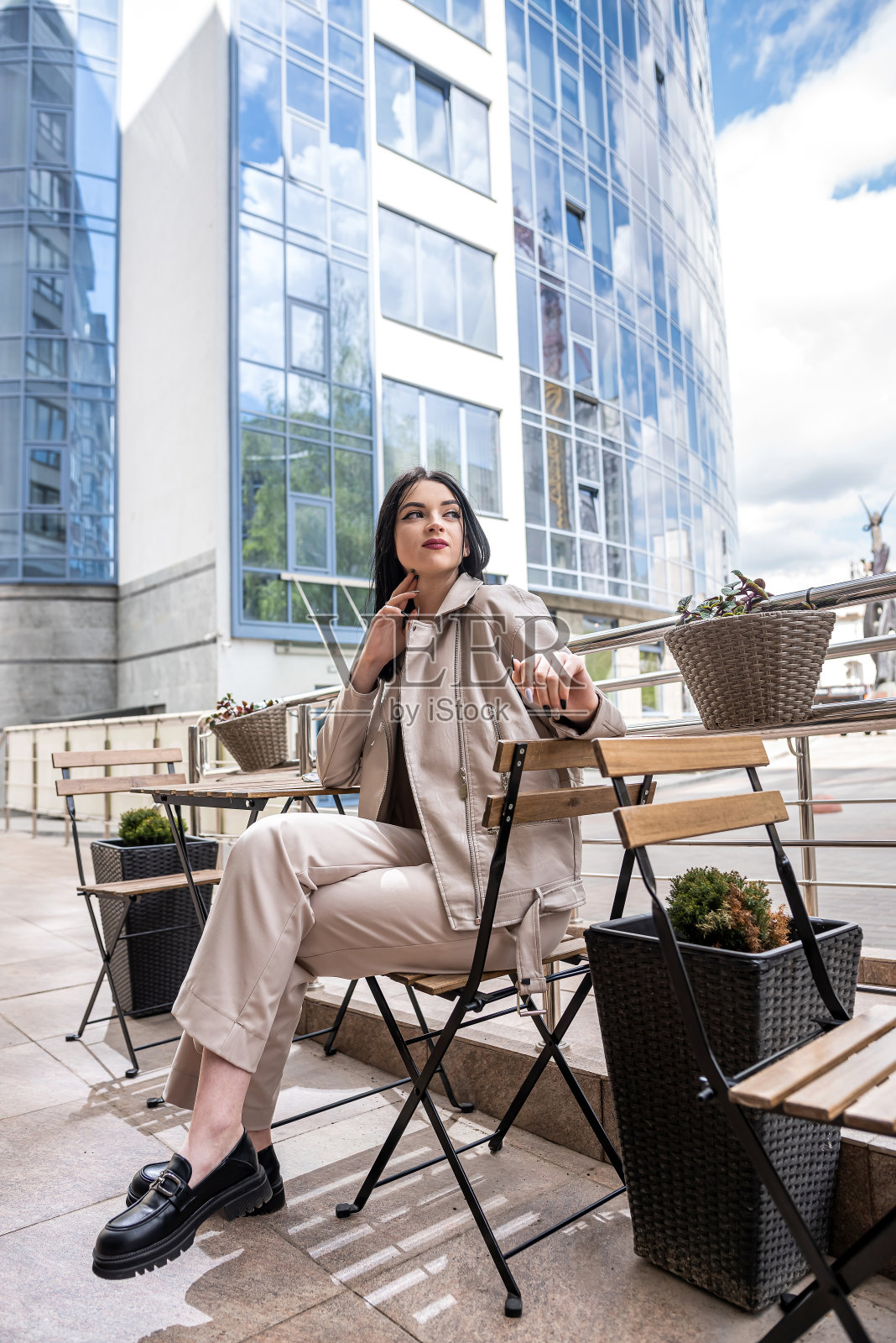 美丽的女孩独自坐在现代商业中心前的一张桌子旁照片摄影图片