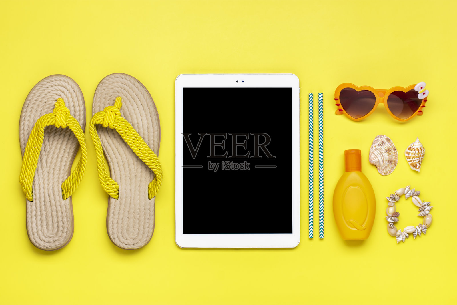 游泳配件-时髦的沙滩人字拖，橙色心形眼镜，贝壳，白色平板，防晒霜在黄色背景平铺俯视图夏天，旅行，聚会，度假的概念照片摄影图片