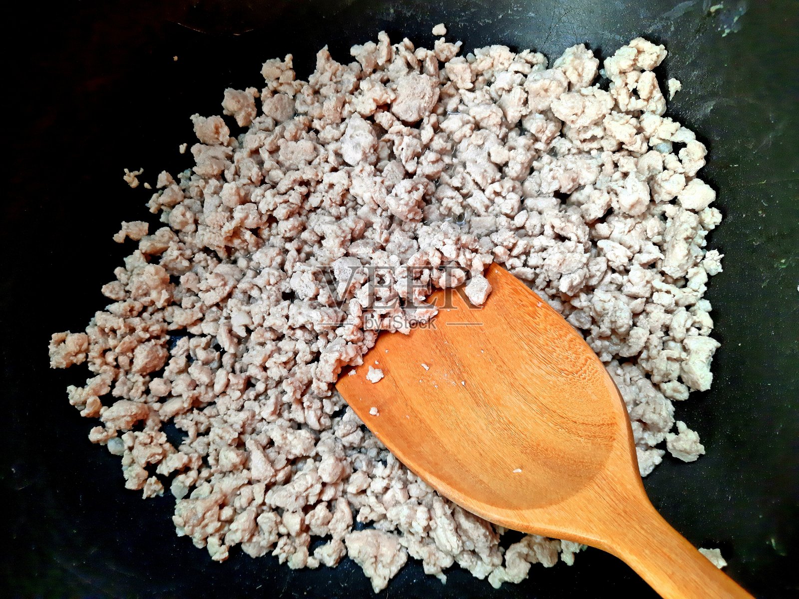 猪肉末和勺子在煮锅-食品准备。照片摄影图片