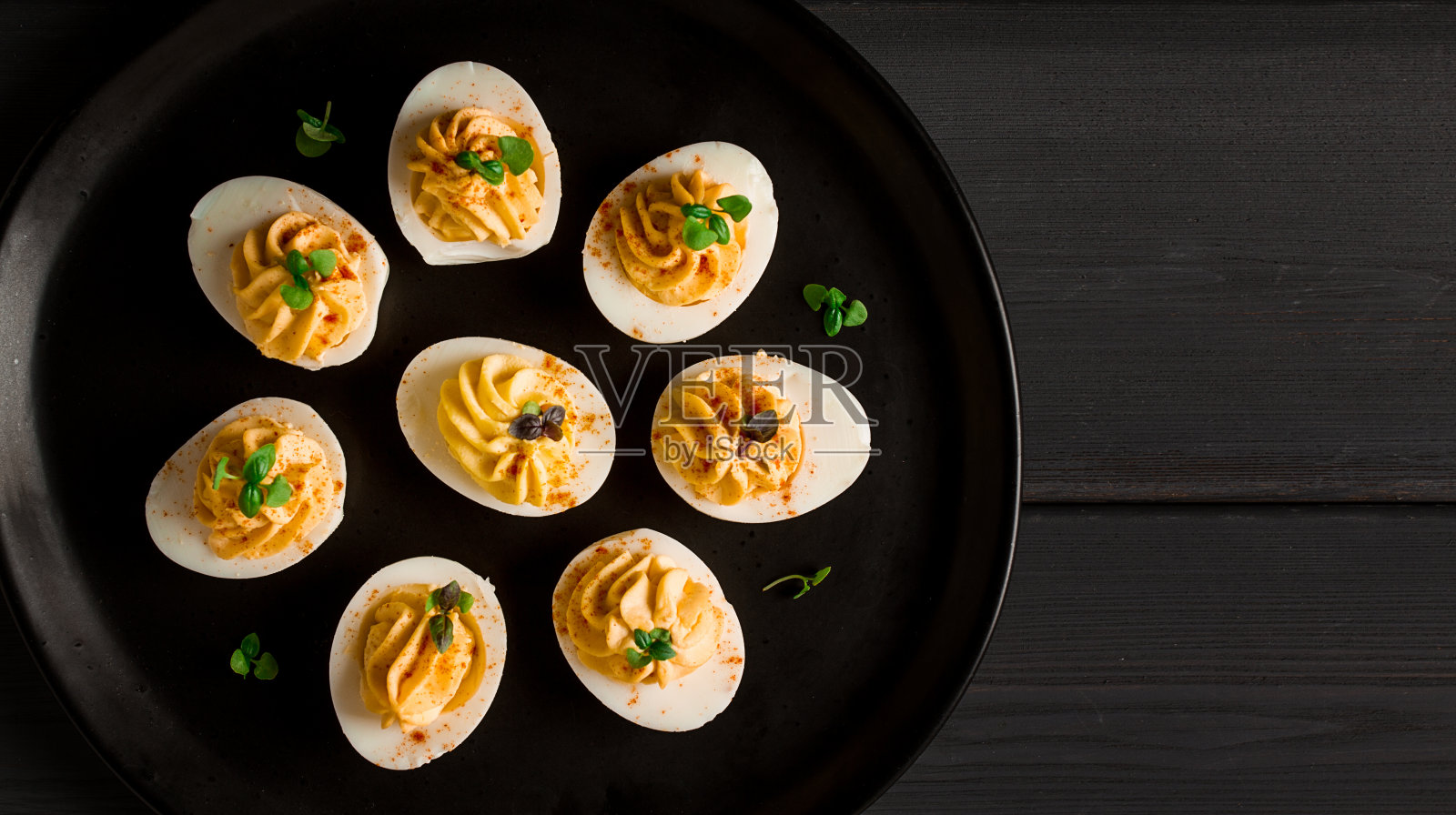 煮熟的鸡蛋里塞满了蛋黄和蛋黄酱，放在一个黑色的盘子里，选择性聚焦，模糊，特写，没有人，照片摄影图片