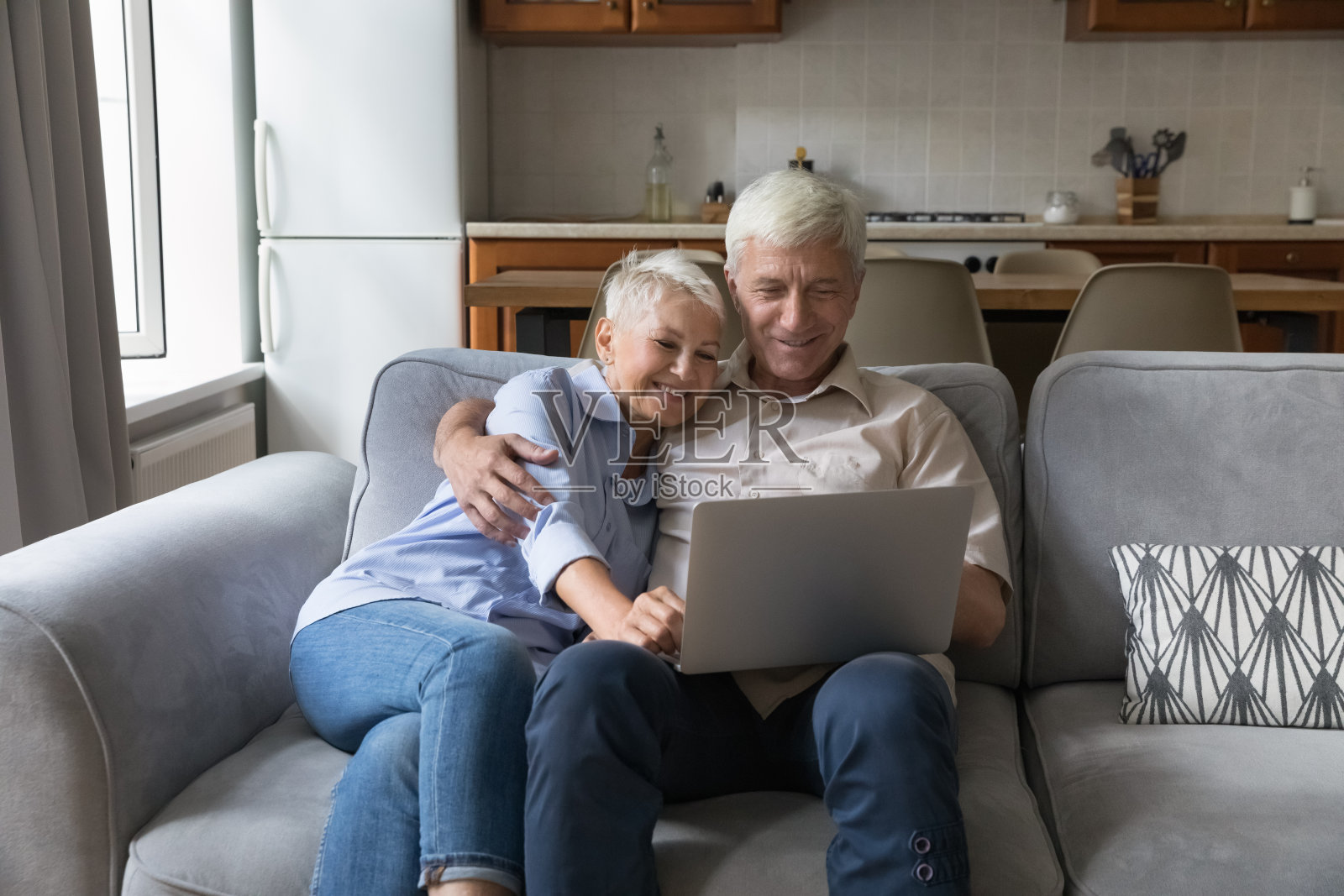 老夫妇坐在沙发上用笔记本电脑看搞笑电影照片摄影图片