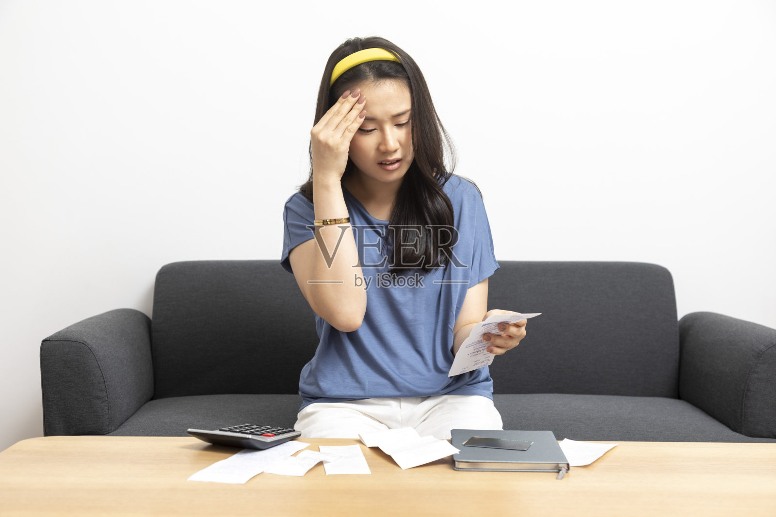 年轻的亚洲女性计算家庭开支和财务，在家里感到沮丧。照片摄影图片