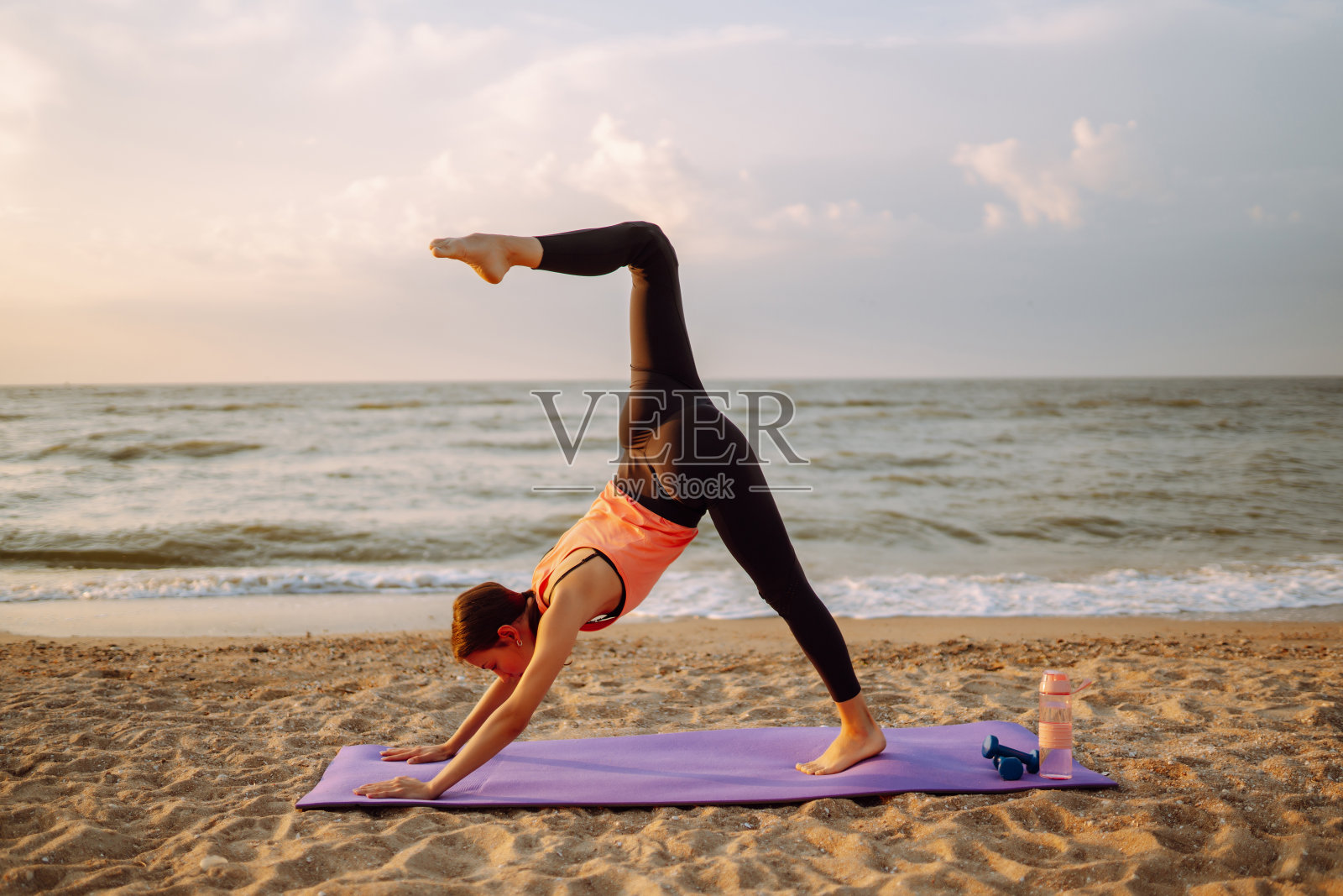 穿着运动服的年轻女子在海滩上做健身运动照片摄影图片