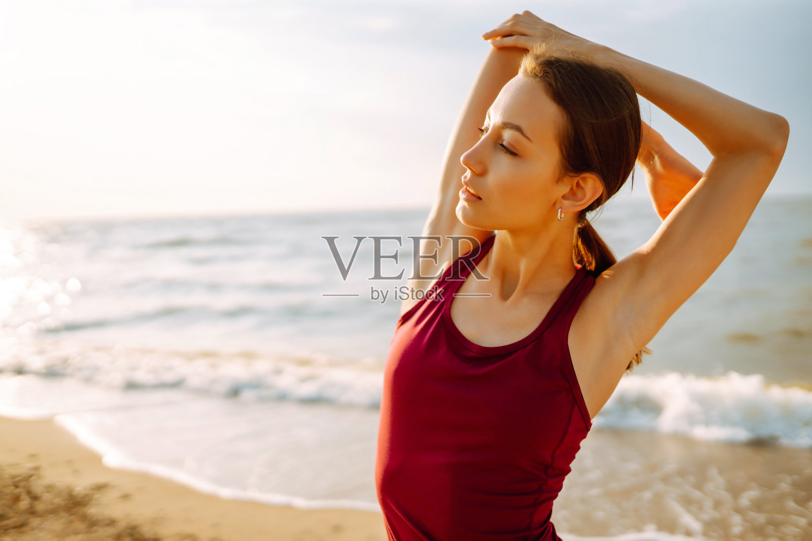 穿着运动服的年轻女子在海滩上做健身运动照片摄影图片